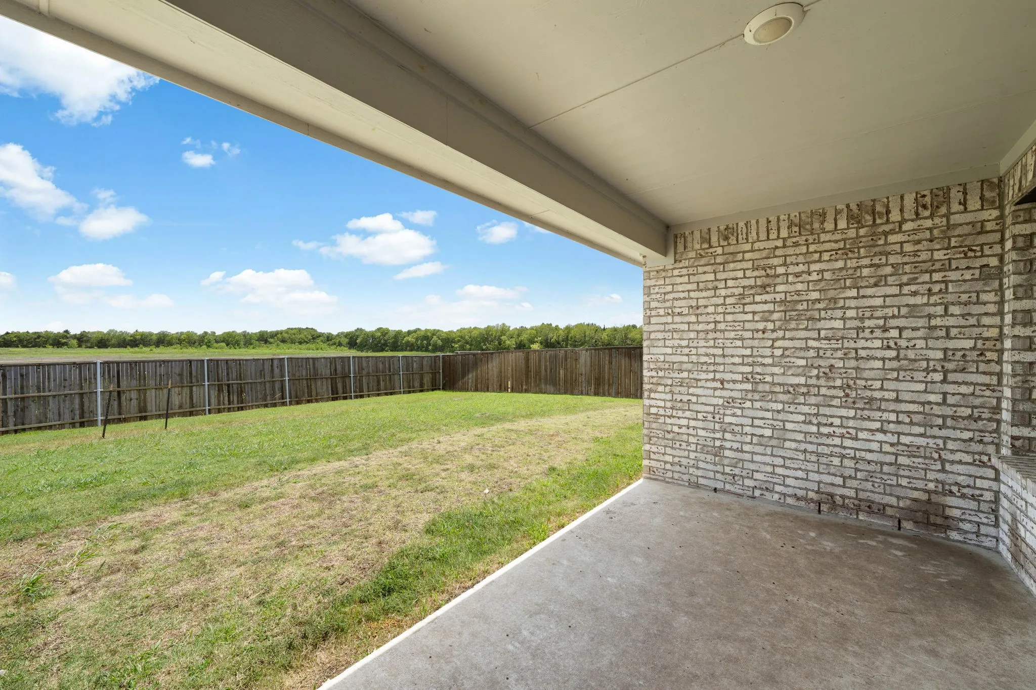 Covered patio with concrete flooring, white brick exterior wall, and recessed ceiling lighting