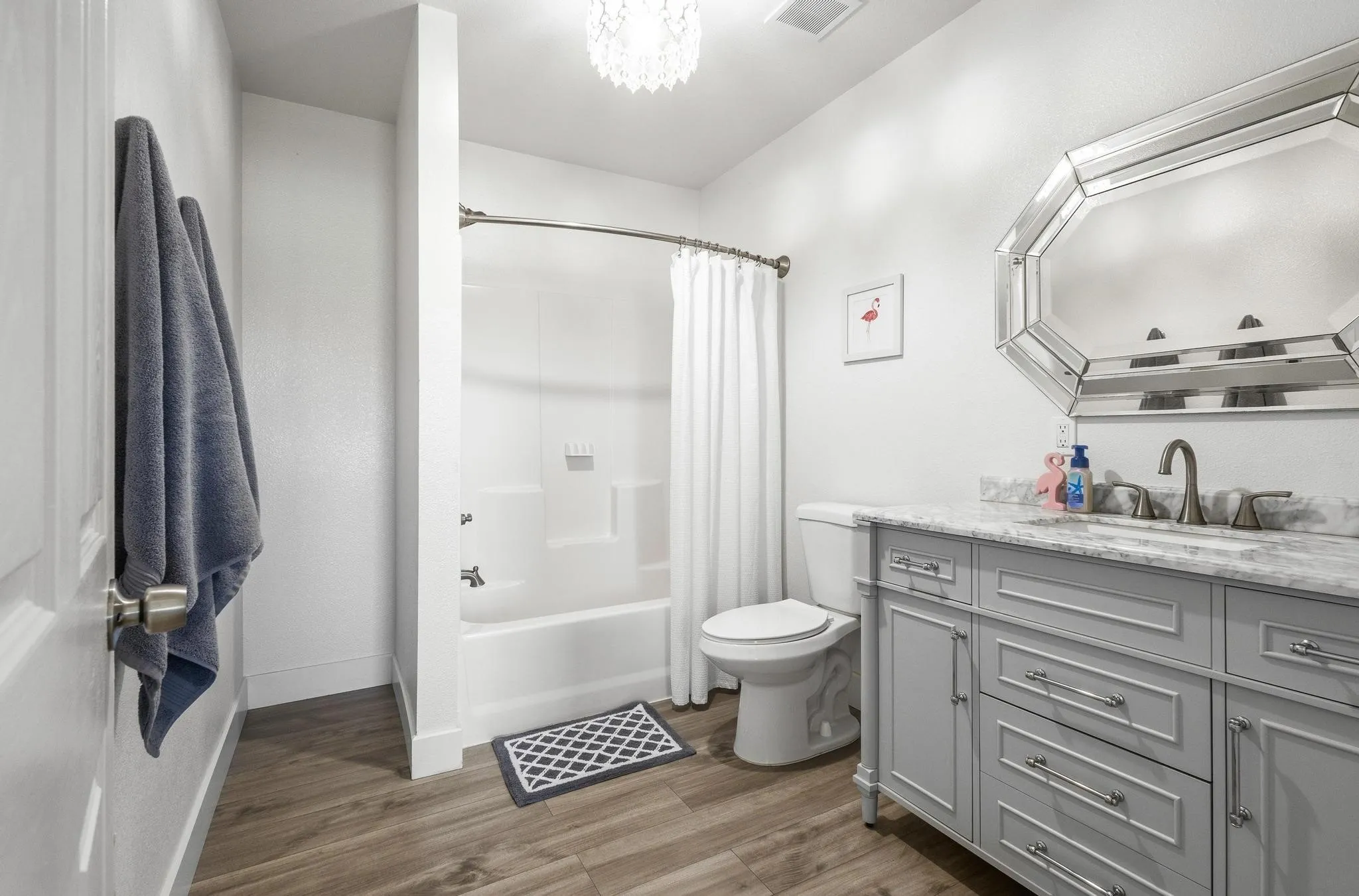 Full bath with vanity, dark wood-style flooring, shower / bath combo with shower curtain, and a chandelier