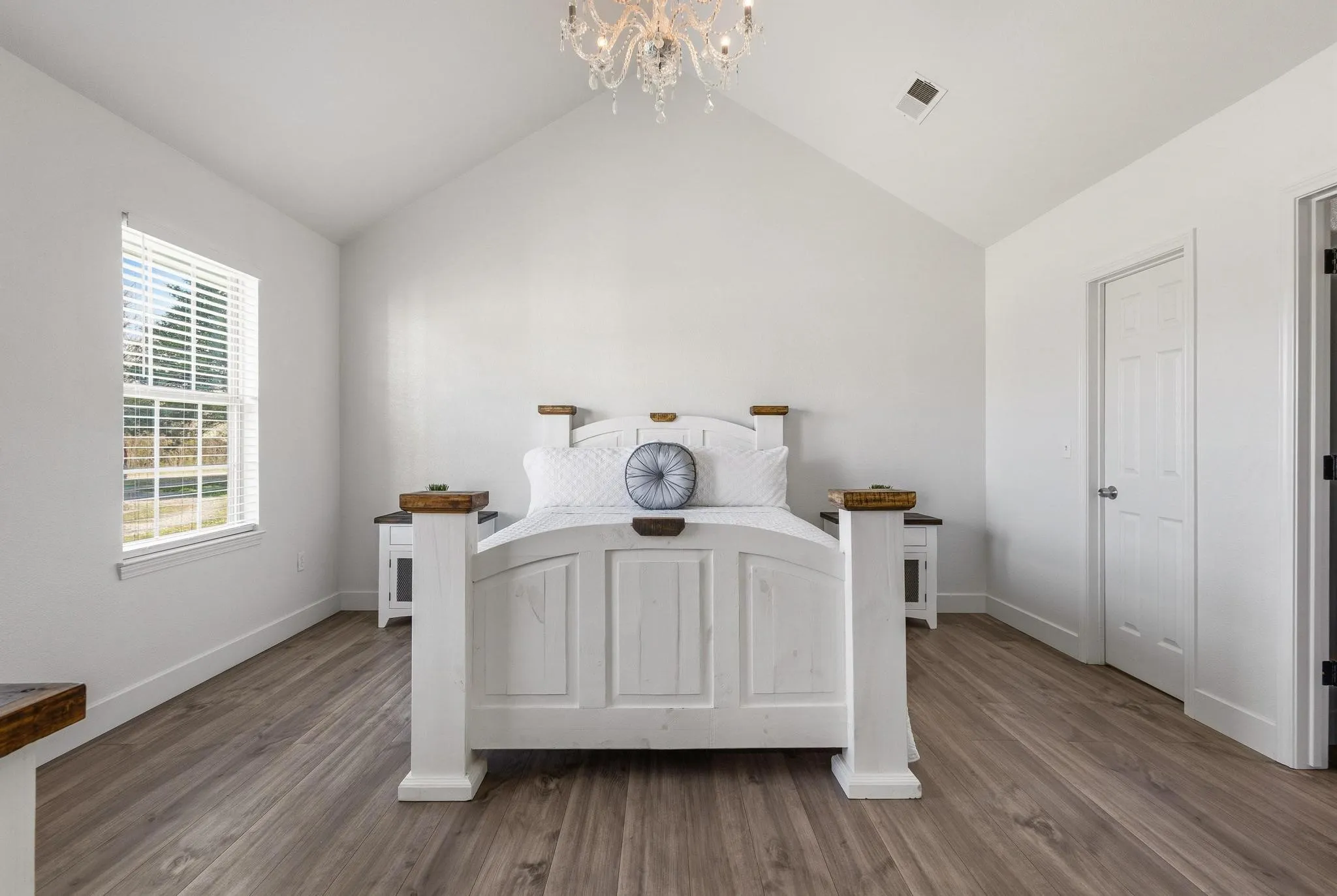 Bedroom with hanging lights and dark wood-style flooring