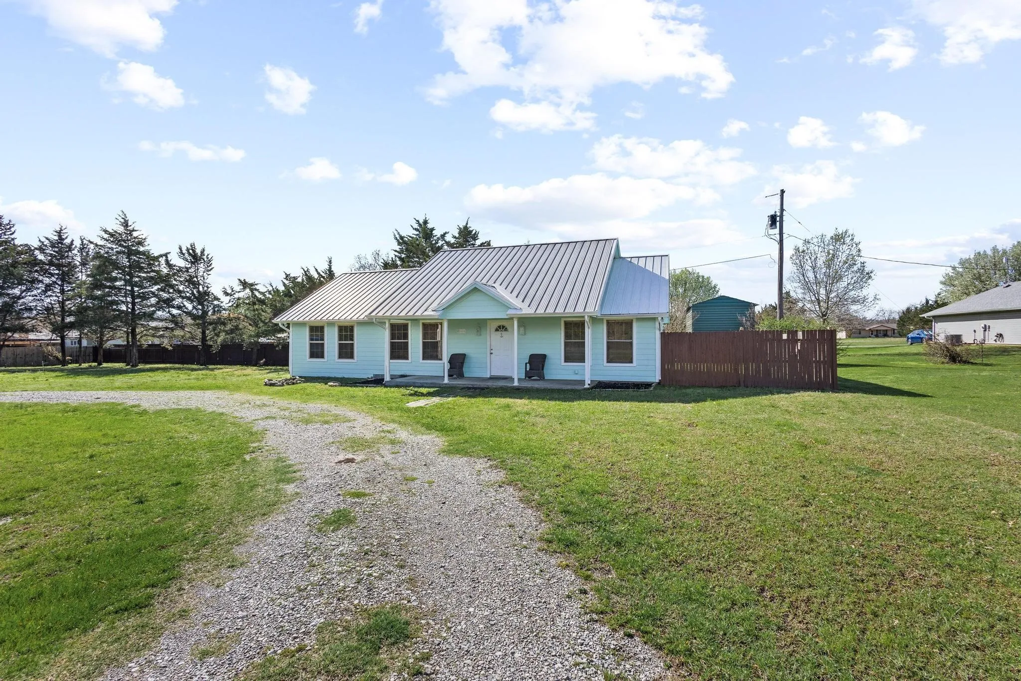 View of front of house featuring a metal roof, driveway, and a porch