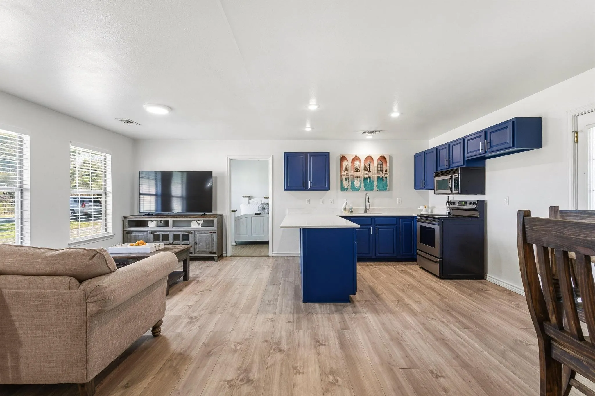 Kitchen with light countertops, blue cabinetry, stainless steel appliances, open floor plan, and light wood finished floors