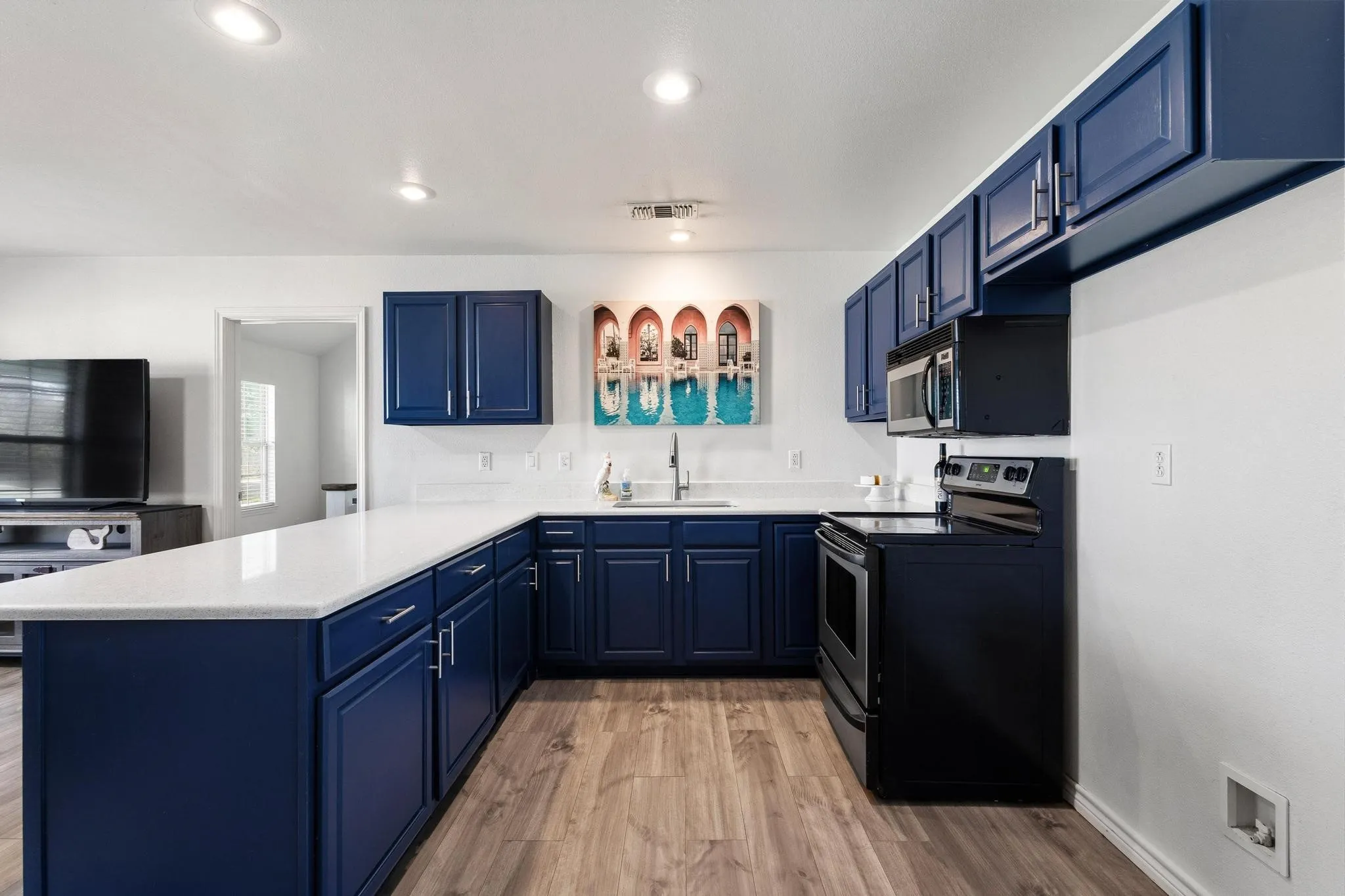 Kitchen with blue cabinets, a peninsula, electric stove, and recessed lighting