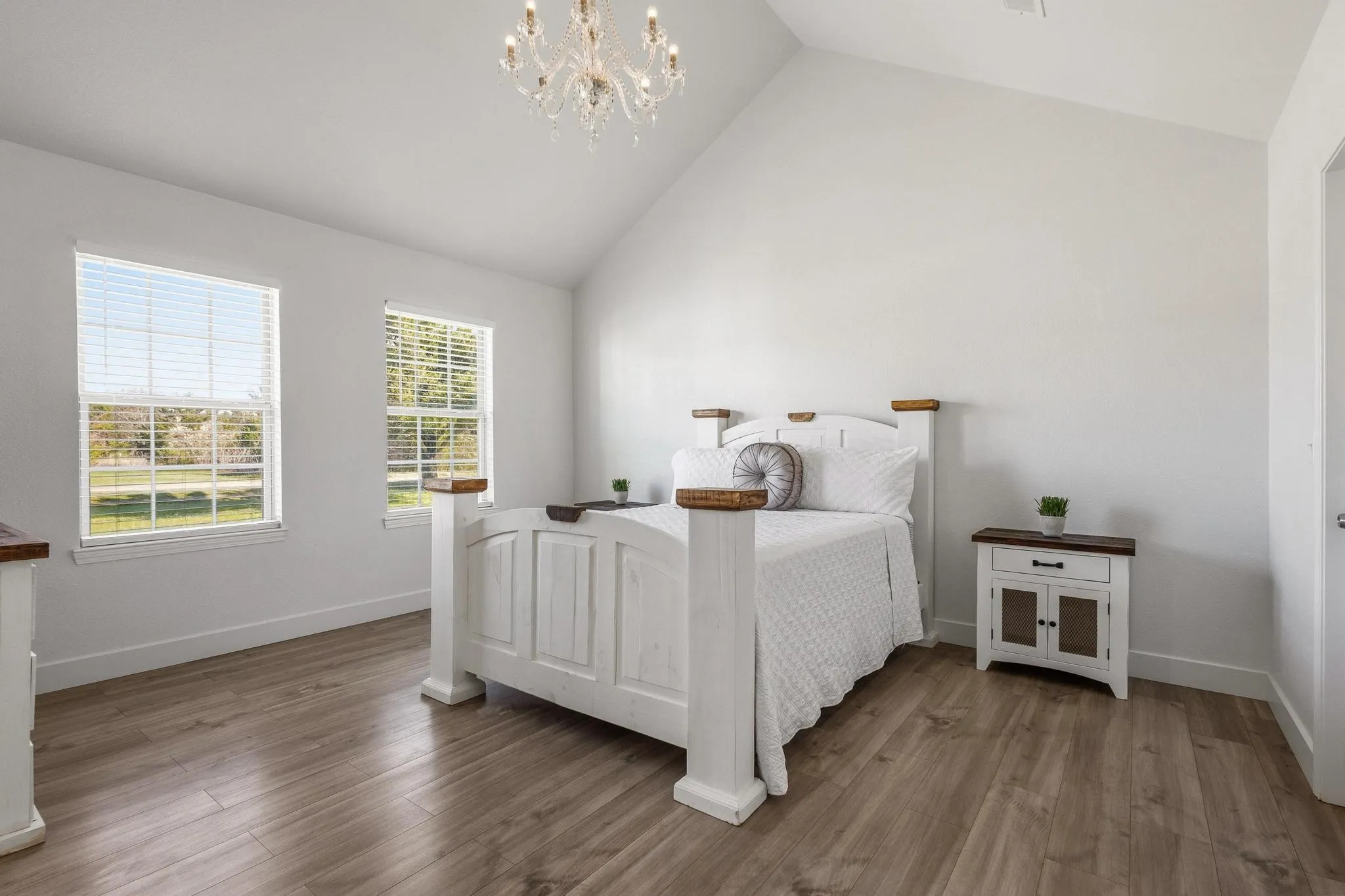 Bedroom featuring suspended lighting, wood finished floors, and a high ceiling