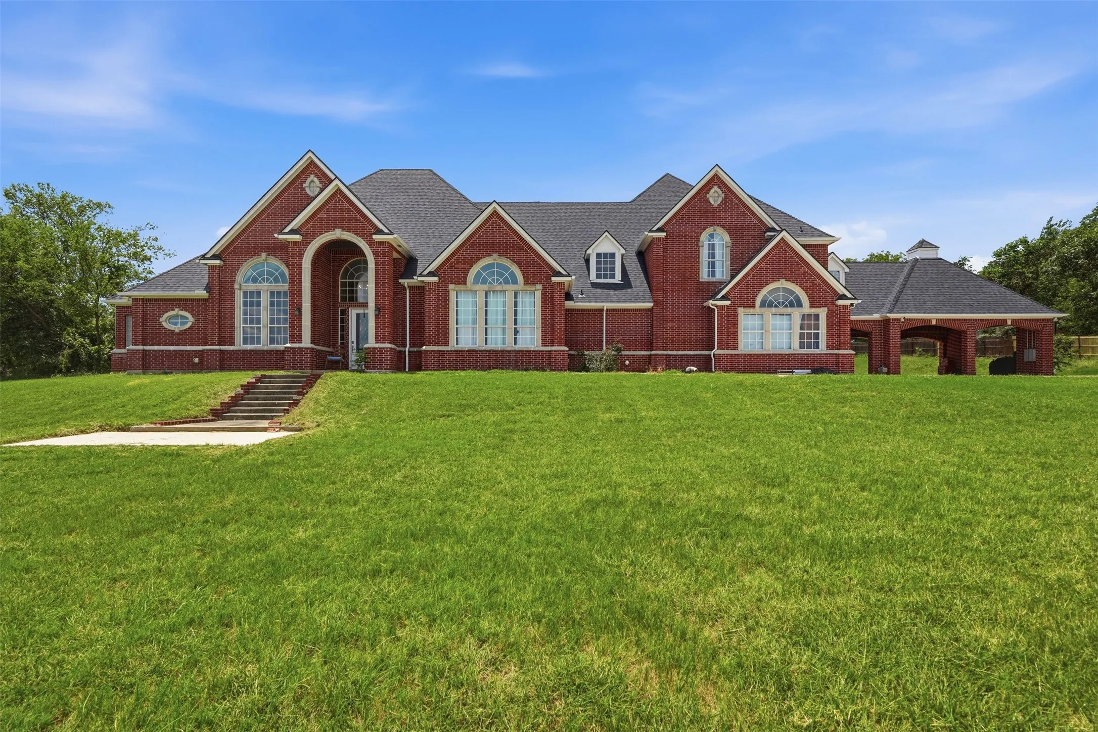 Brick exterior residence featuring a prominent arched entry, multiple arched windows, and a portico with an attached cupola