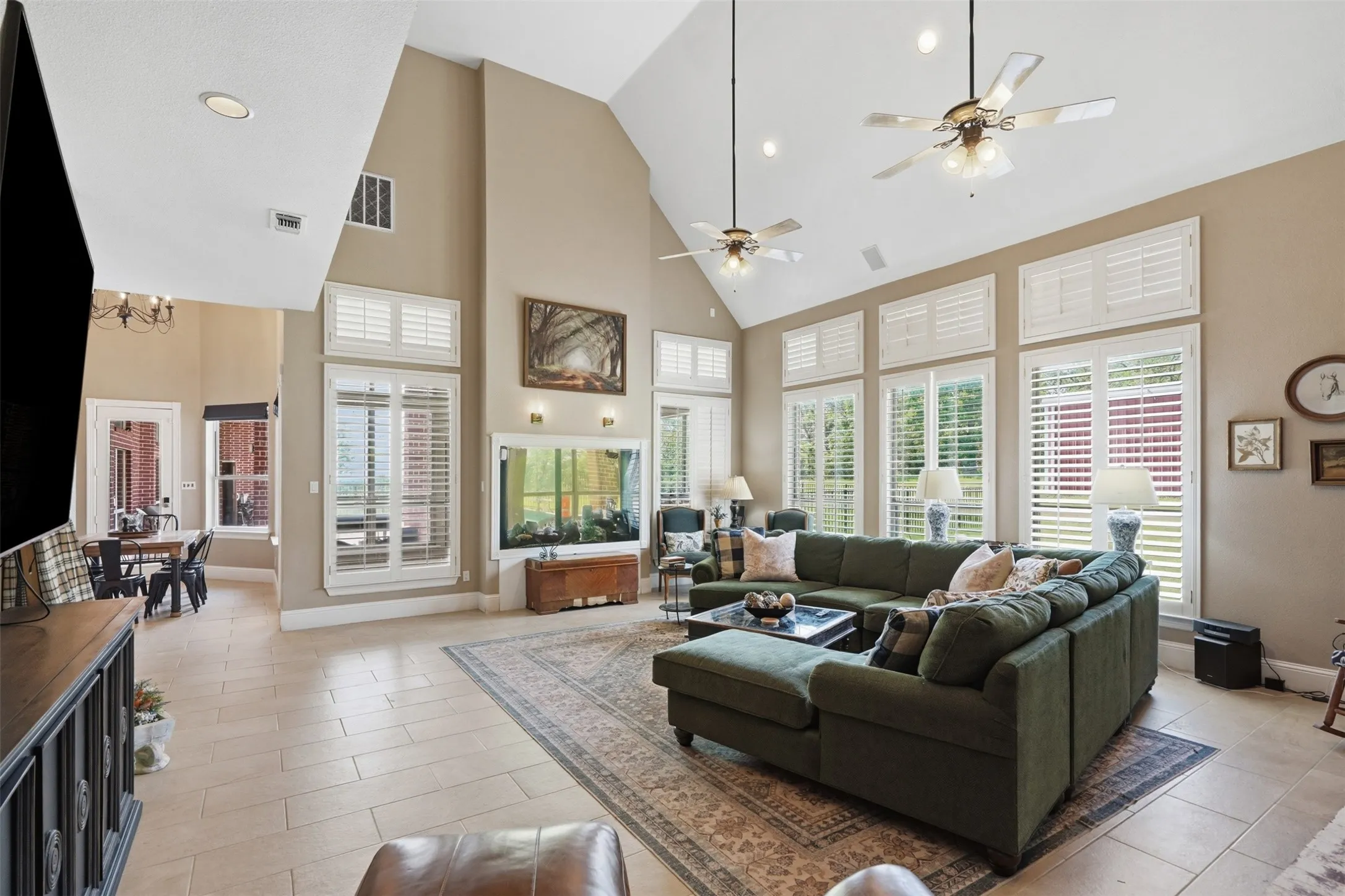 Spacious living area featuring a vaulted ceiling with recessed lighting and ceiling fans