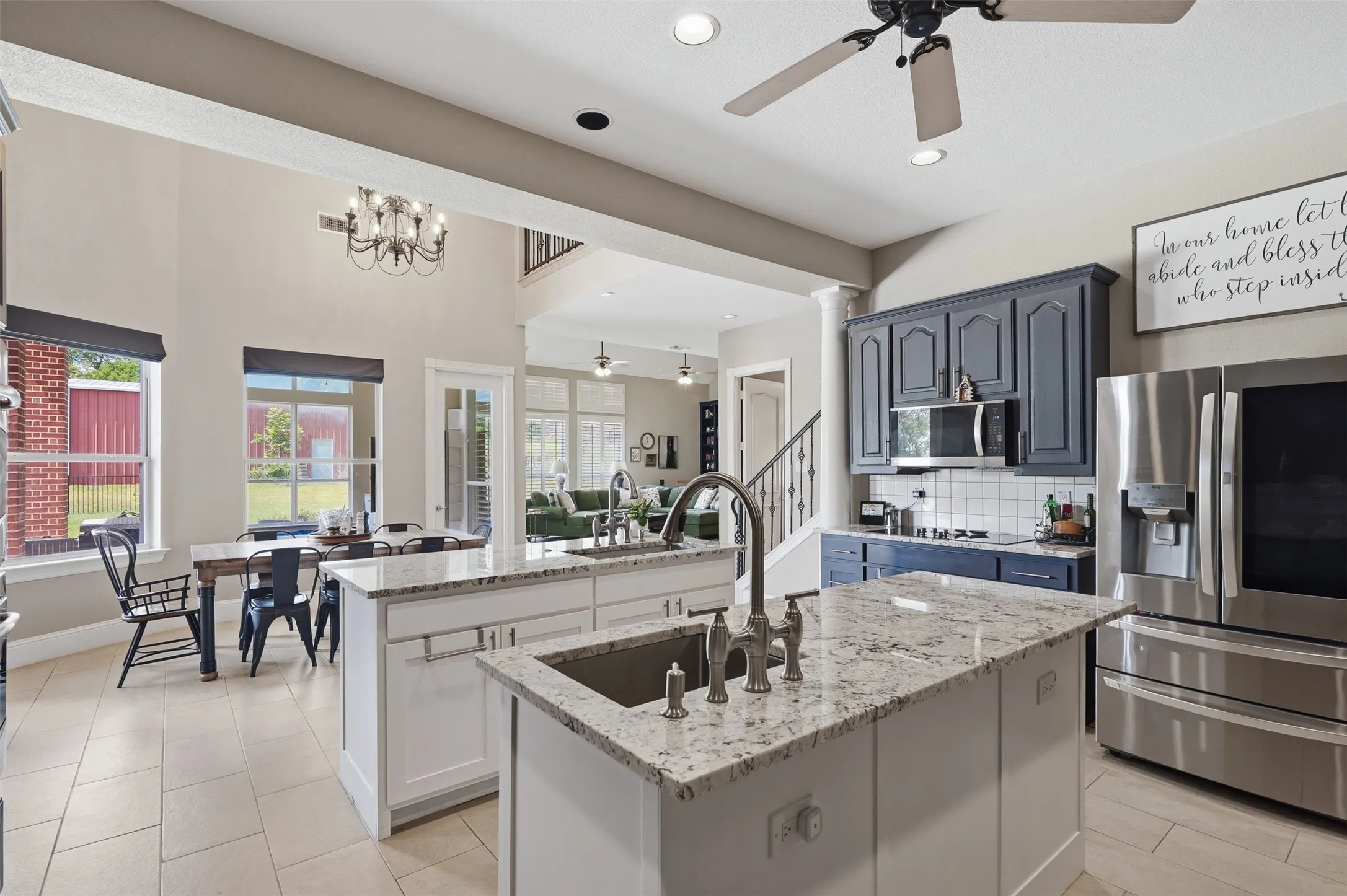 Open-concept kitchen with dual islands featuring granite countertops, a stainless steel sink, and a high-arch faucet