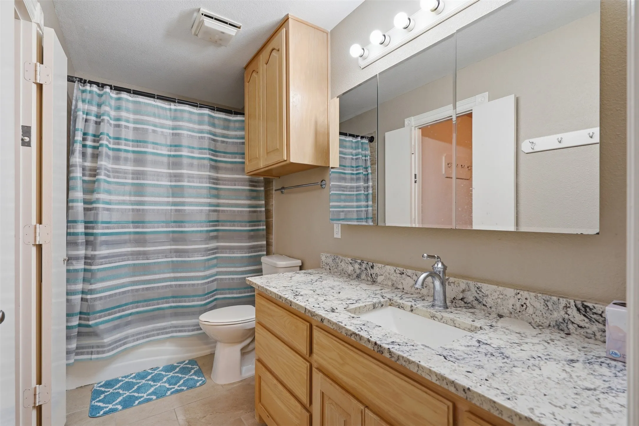 Bathroom featuring a spacious vanity with a light-colored, patterned countertop, an integrated rectangular sink, and a chrome faucet