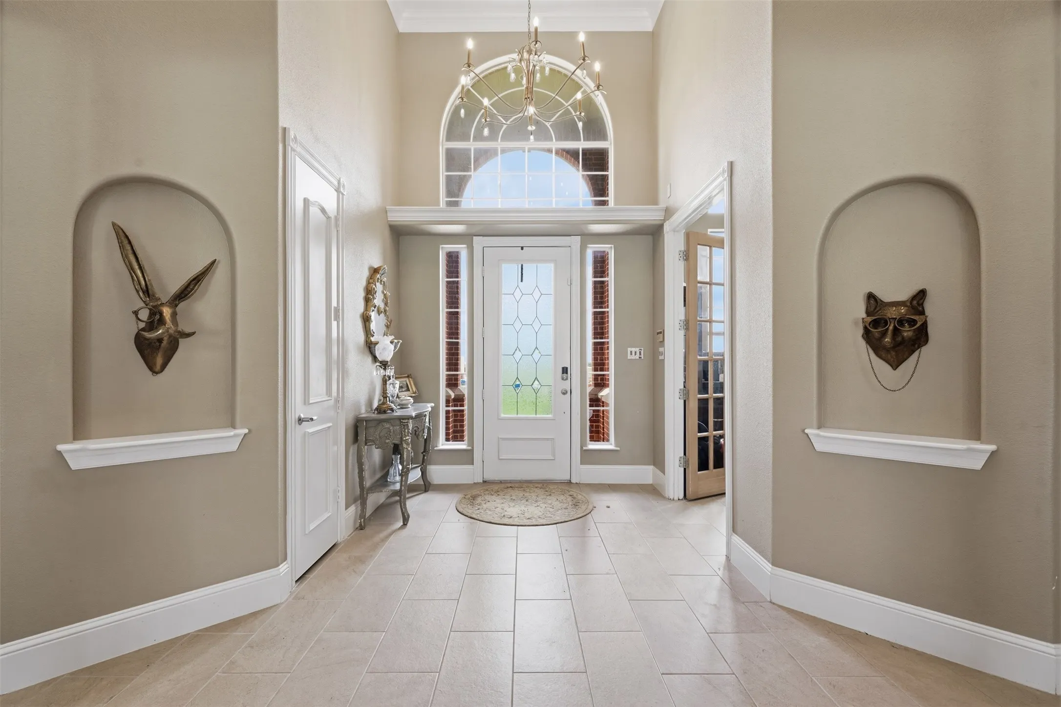 Two-story foyer featuring large format tile flooring and arched wall niches with display ledges