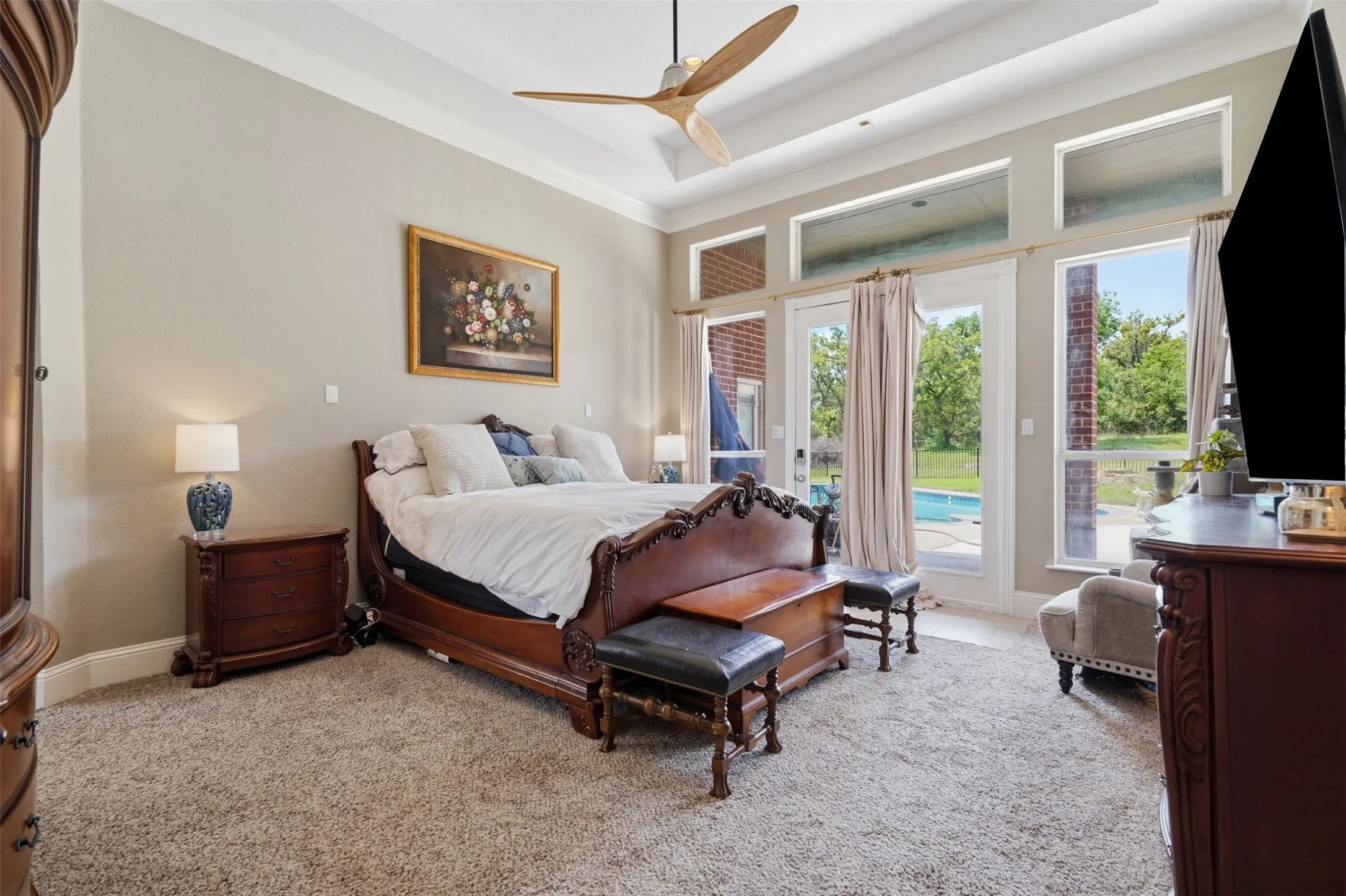 Carpeted bedroom featuring a contemporary ceiling fan and tray ceiling