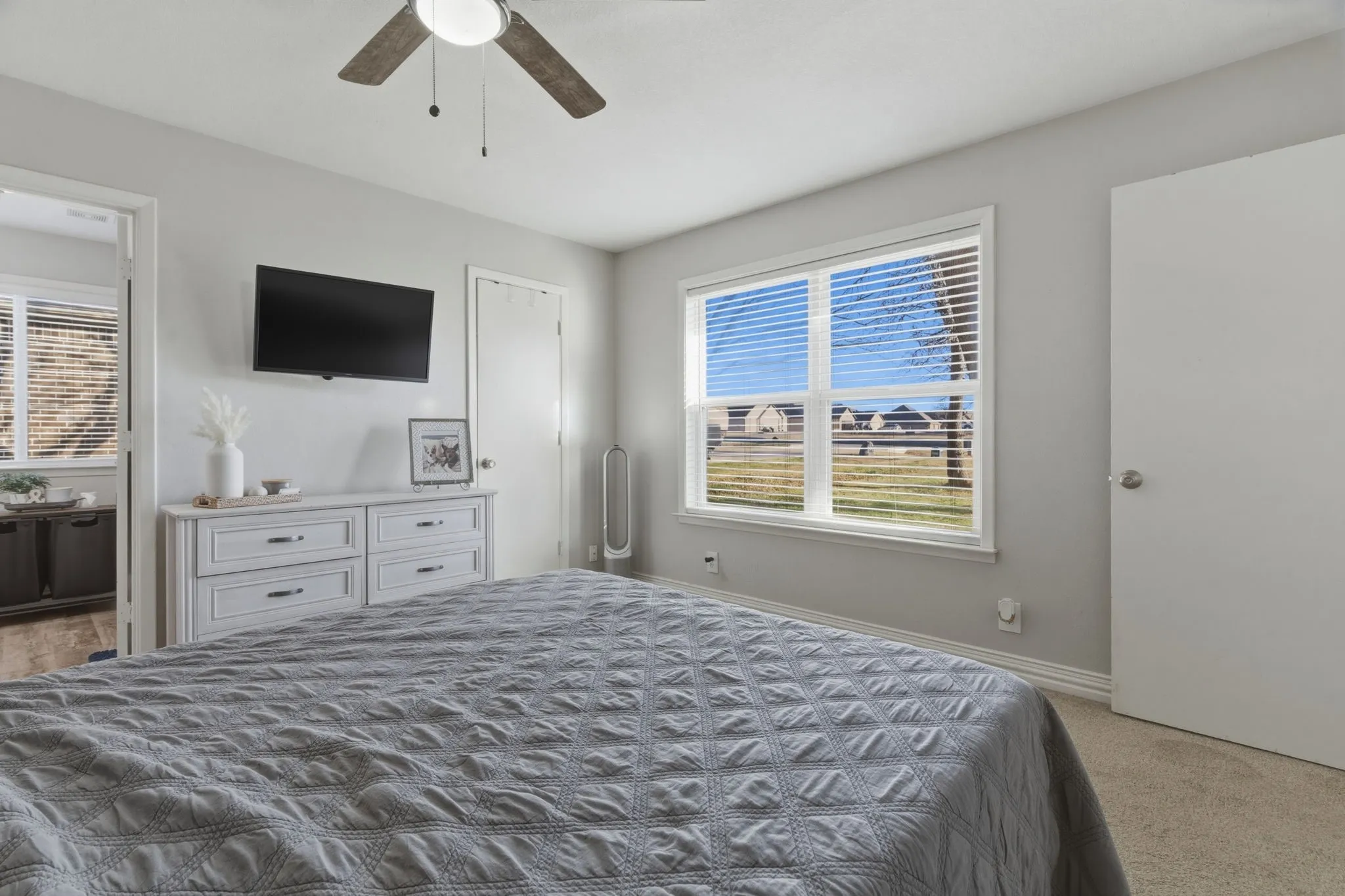 Bedroom featuring multiple windows, light colored carpet, a ceiling fan, and ensuite bathroom