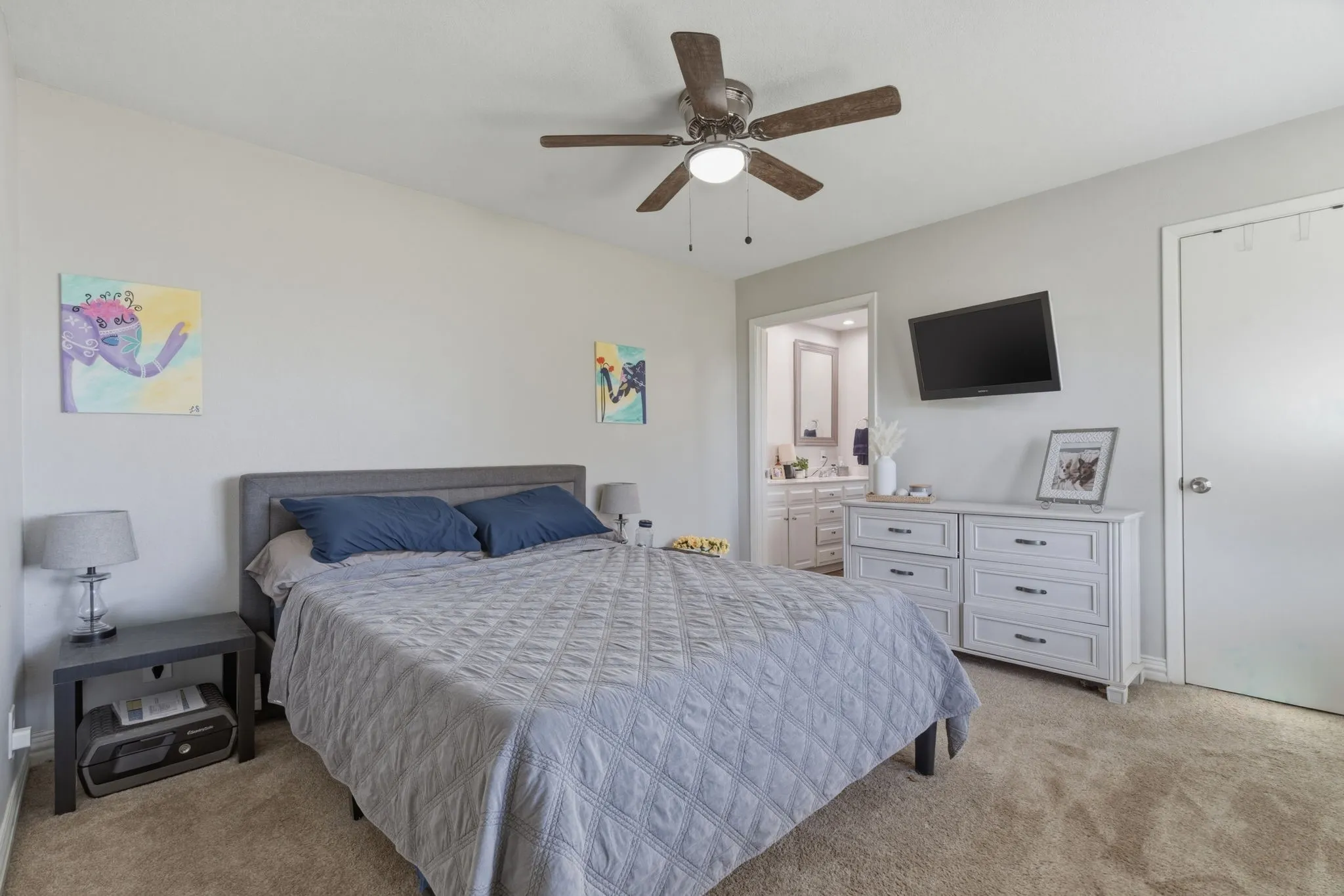 Bedroom featuring light carpet, a ceiling fan, and connected bathroom