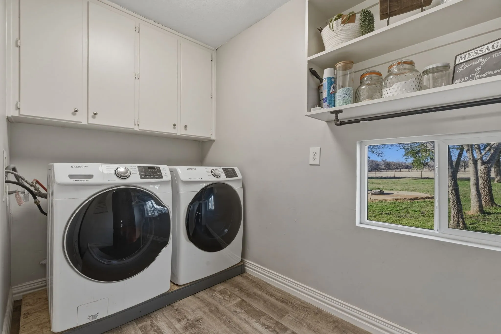 Laundry room with light wood-style flooring, washer and clothes dryer, and cabinet space