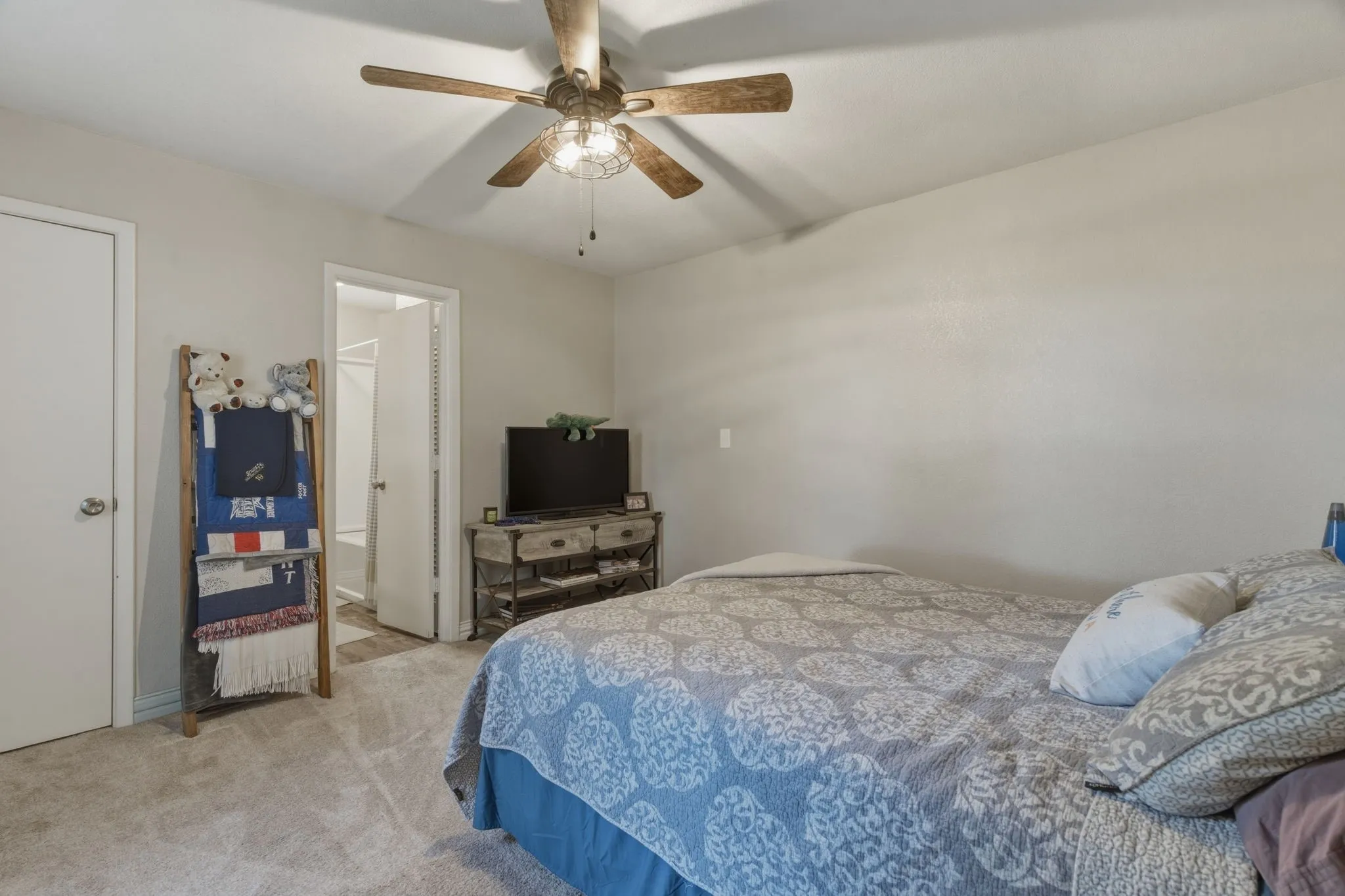 Bedroom featuring light colored carpet, a ceiling fan, and ensuite bathroom