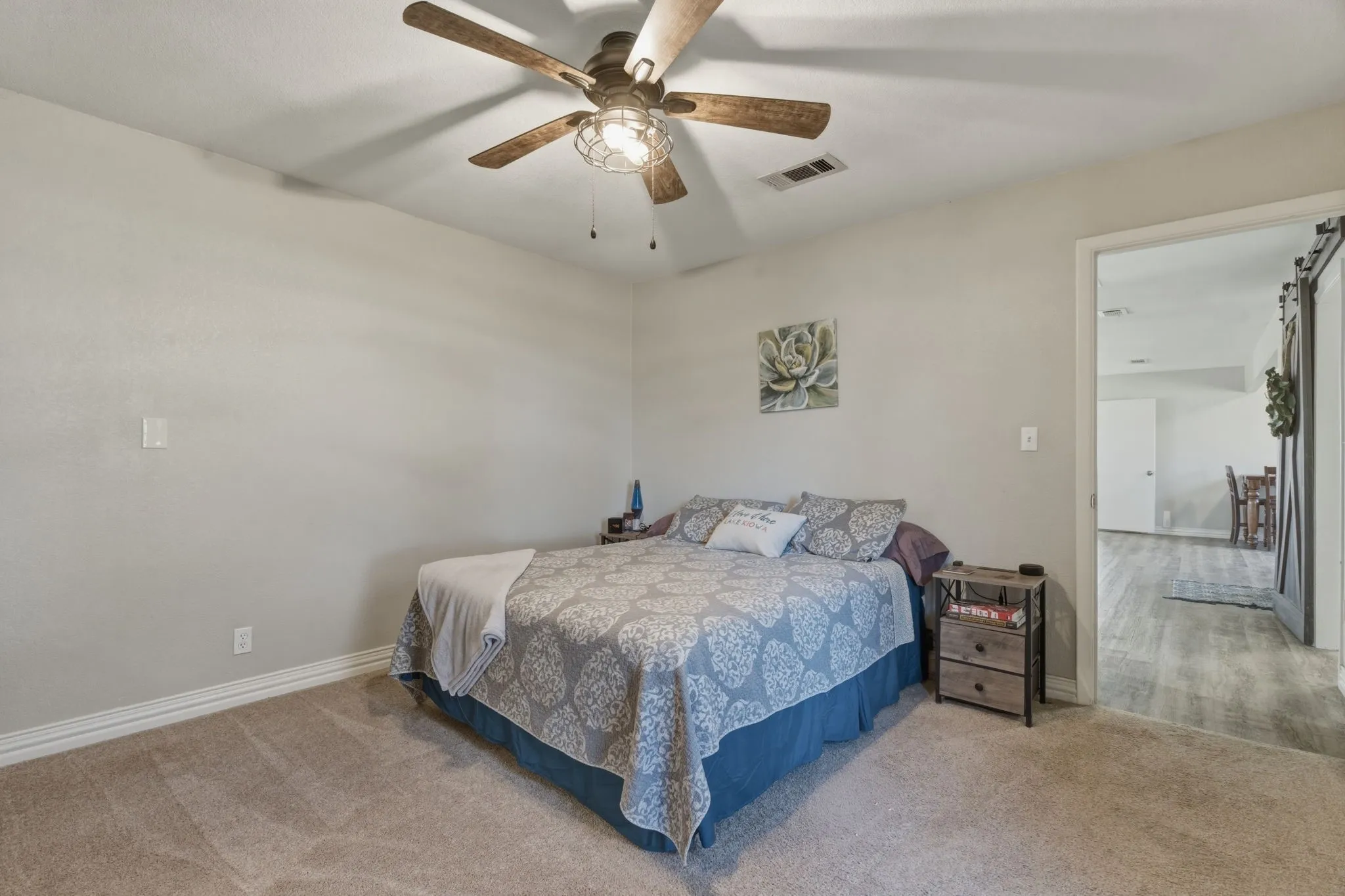 Carpeted bedroom with a ceiling fan and a barn door