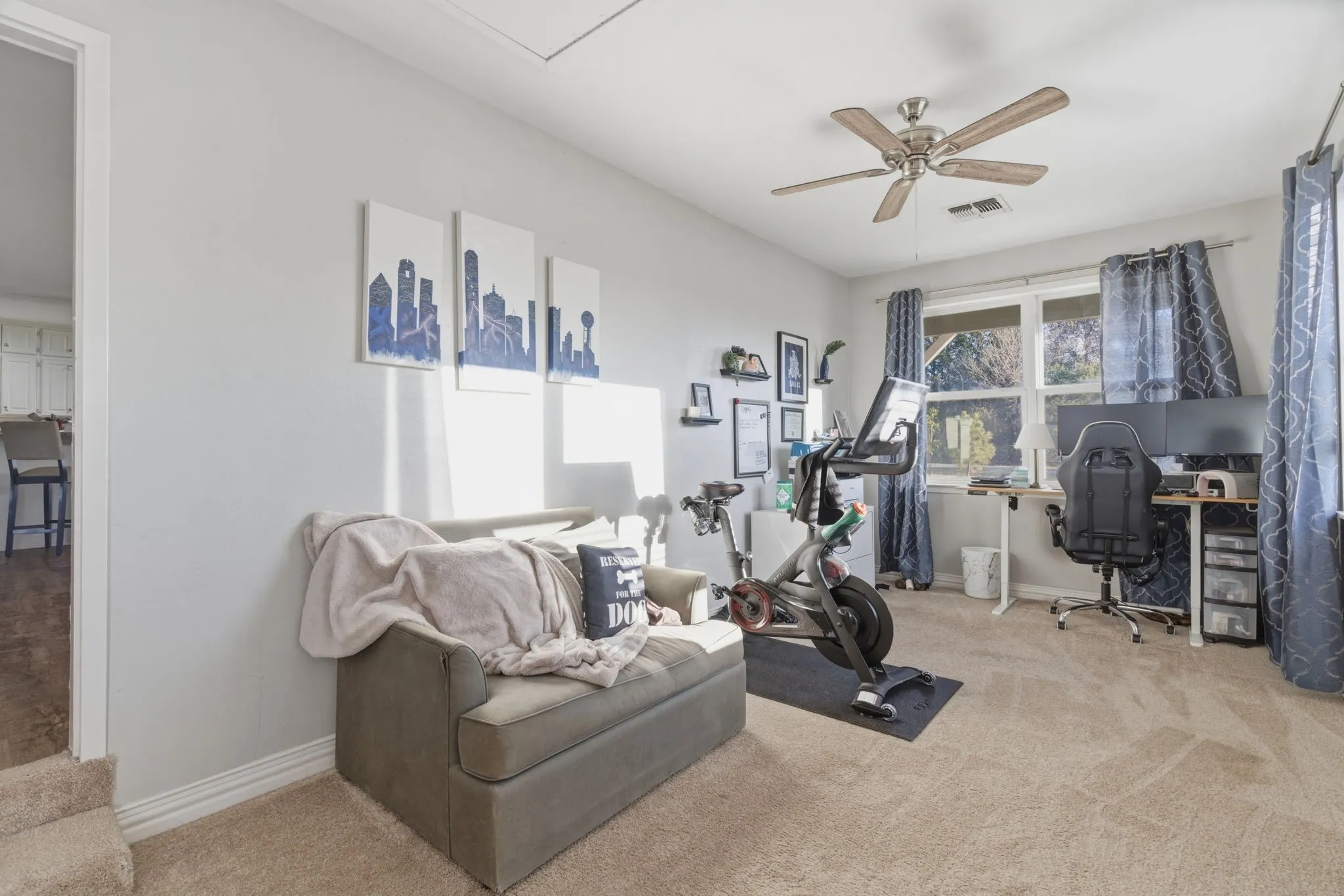 Exercise room with light colored carpet and a ceiling fan