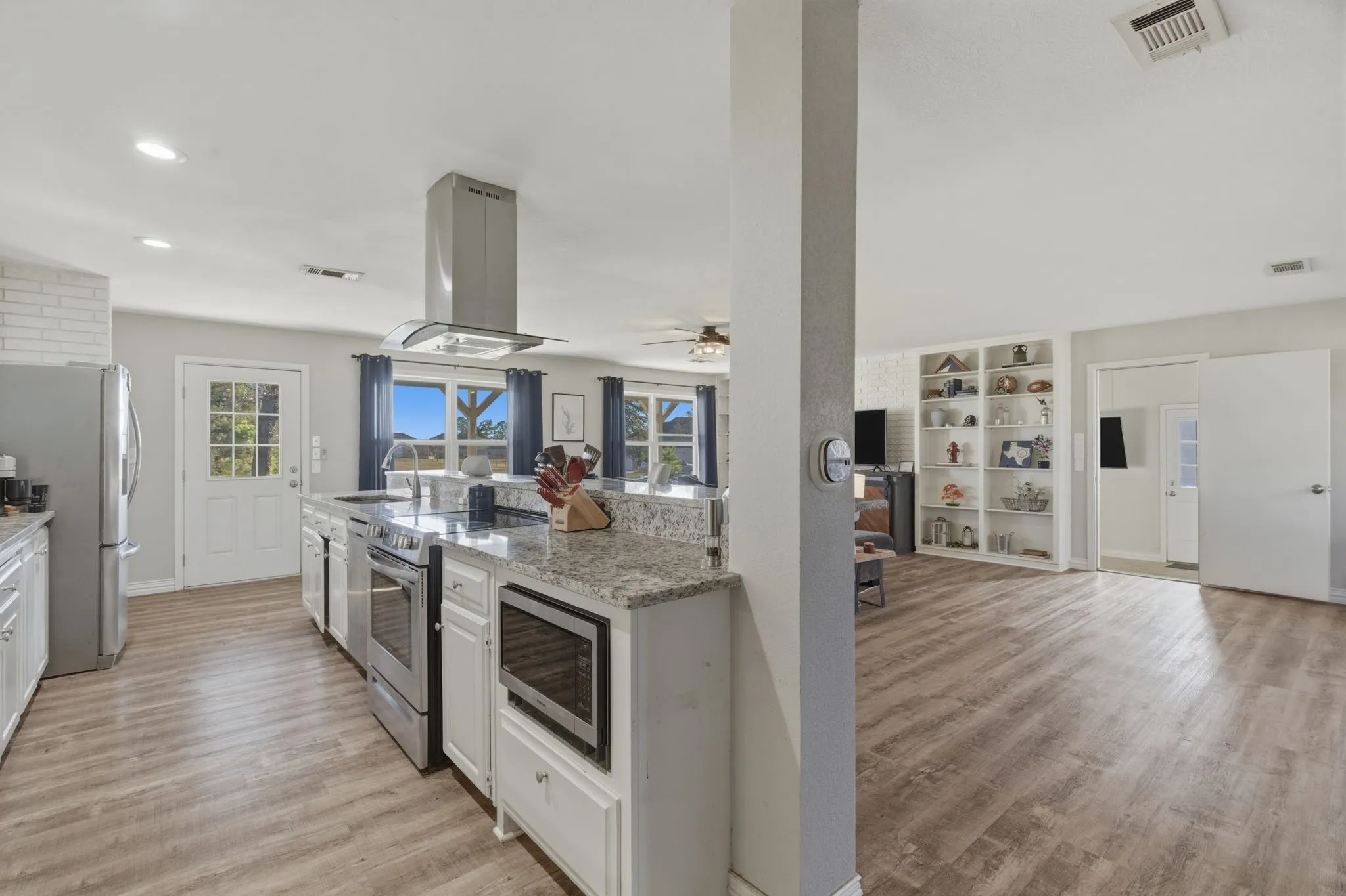 Kitchen featuring built in shelves, stainless steel appliances, light wood-style floors, open floor plan, and recessed lighting