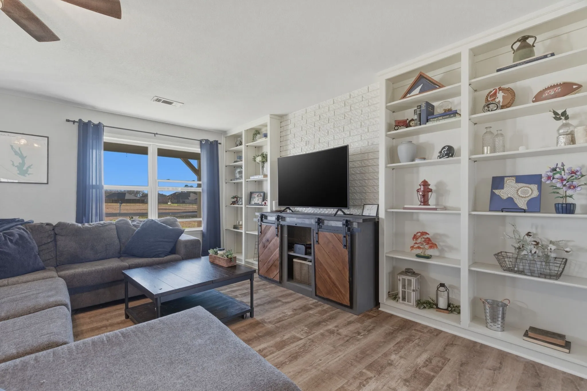 Living area with light wood-style flooring, a ceiling fan, and built in shelves