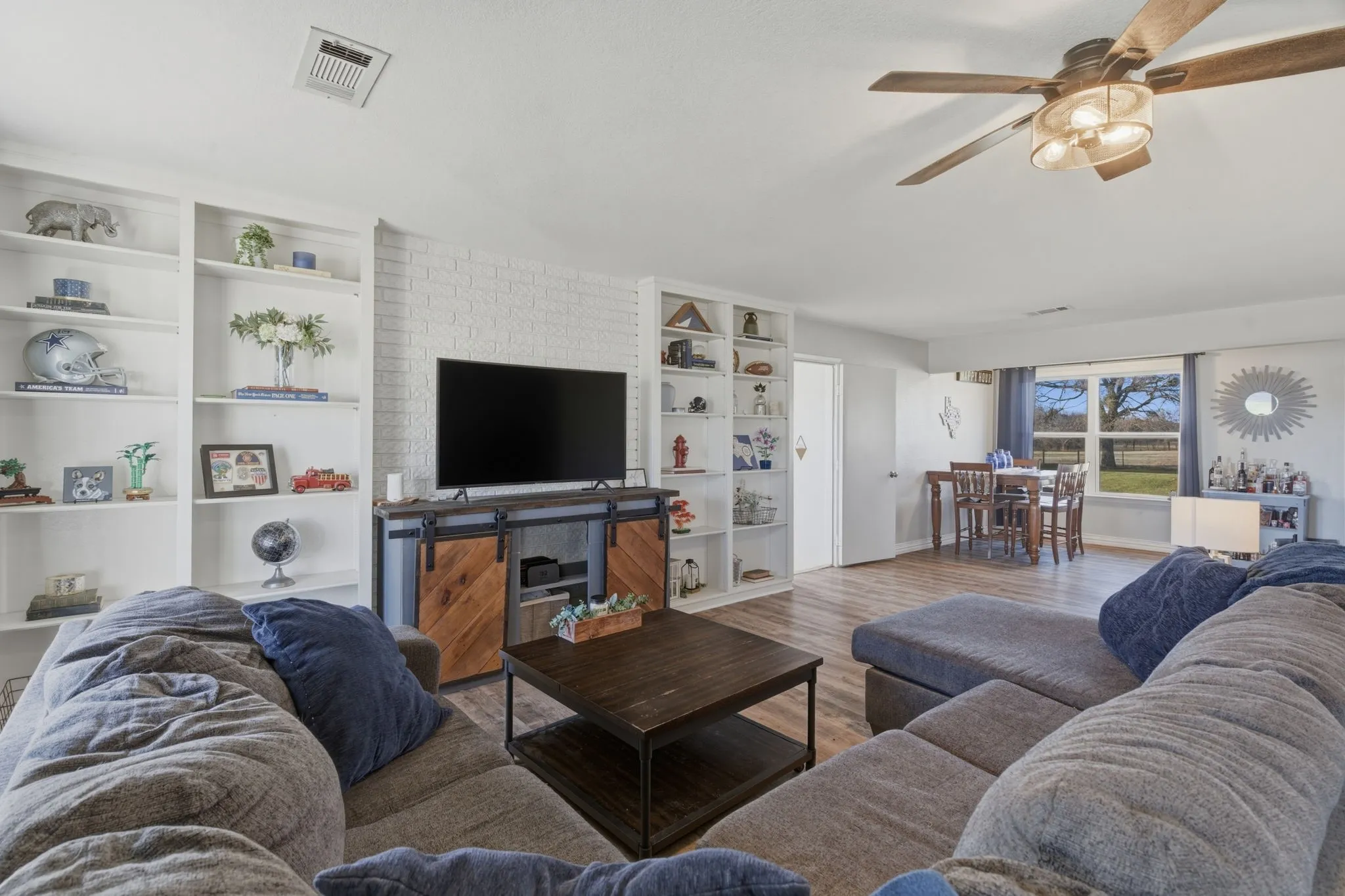 Living area featuring a ceiling fan, built in features, and wood finished floors
