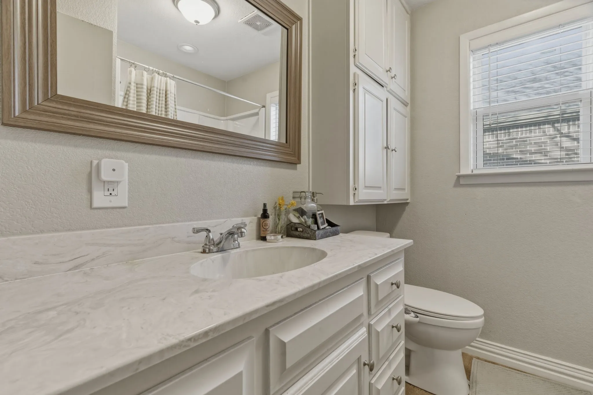 Bathroom with a textured wall, a shower with curtain, and vanity
