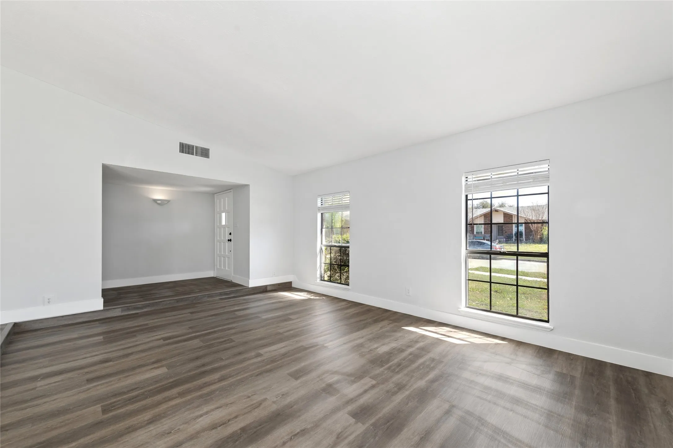 Unfurnished living room featuring dark wood finished floors and lofted ceiling