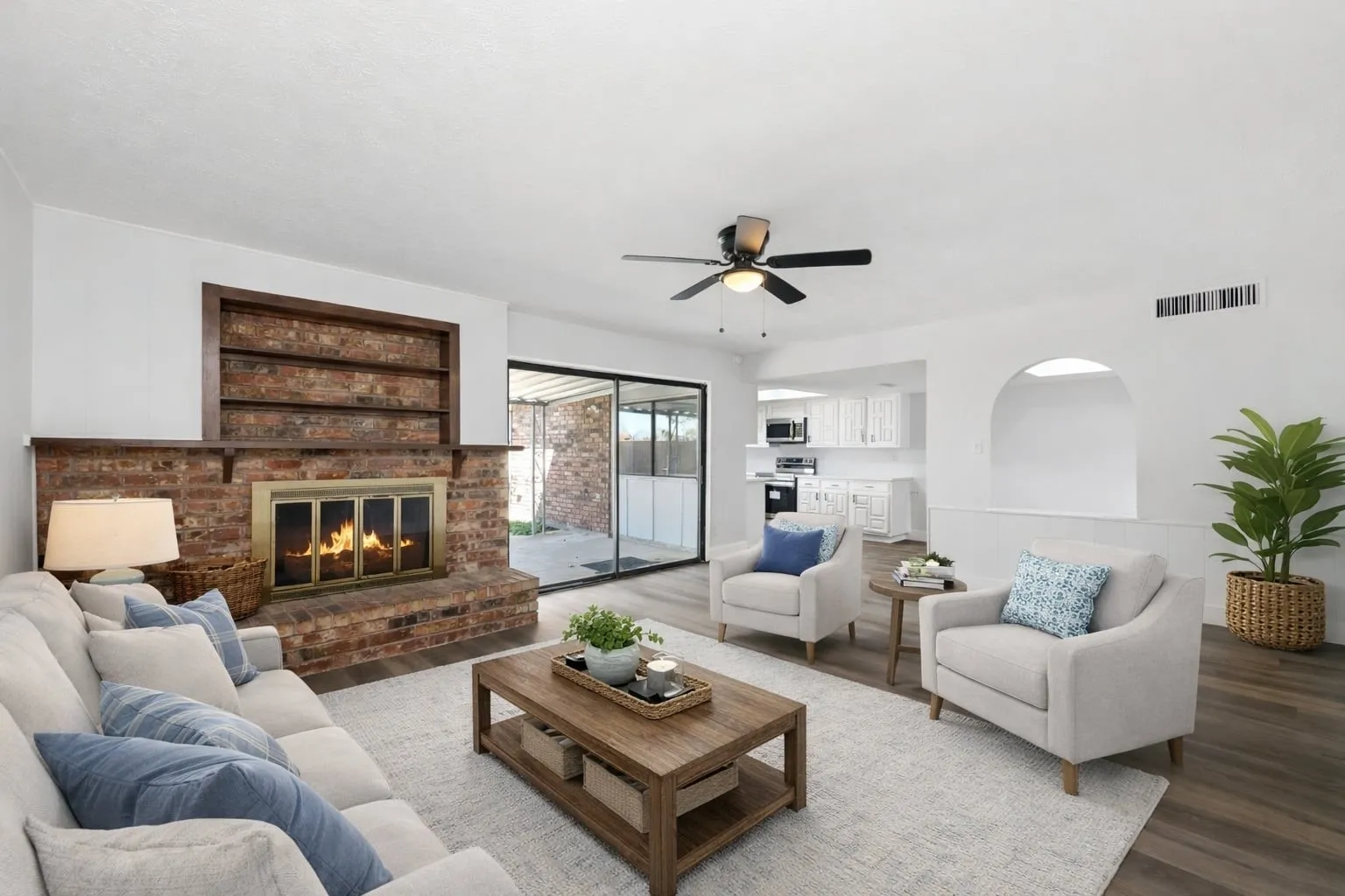 Living room featuring a brick fireplace, wood finished floors, and ceiling fan