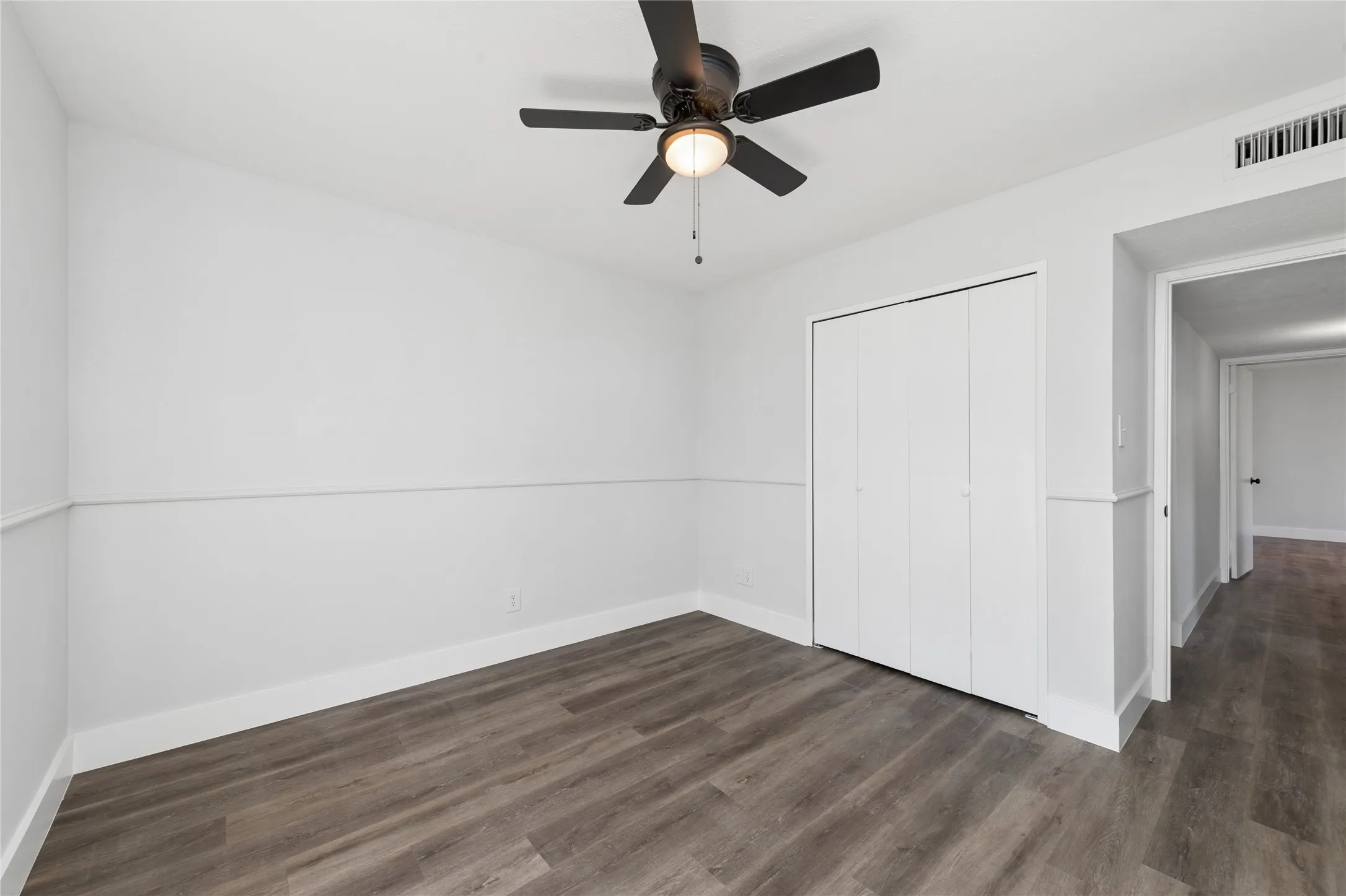 Unfurnished bedroom featuring dark wood-type flooring, ceiling fan, and a closet