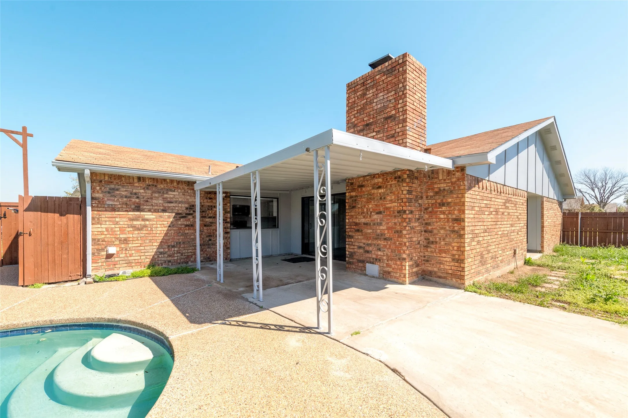 Back of house with brick siding, a patio area, a gate, a chimney, and board and batten siding