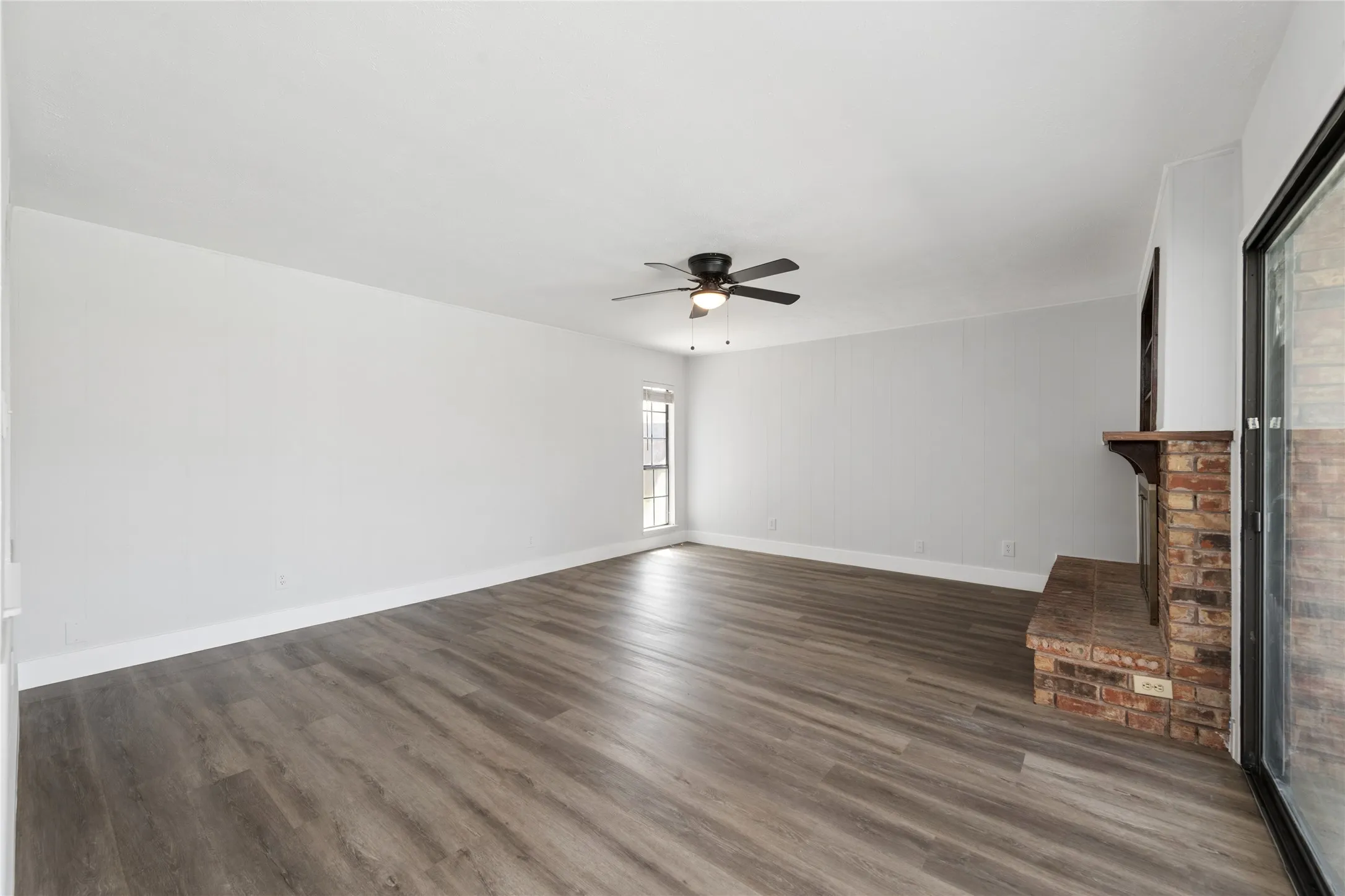 Unfurnished living room with a ceiling fan, dark wood-type flooring, and a fireplace