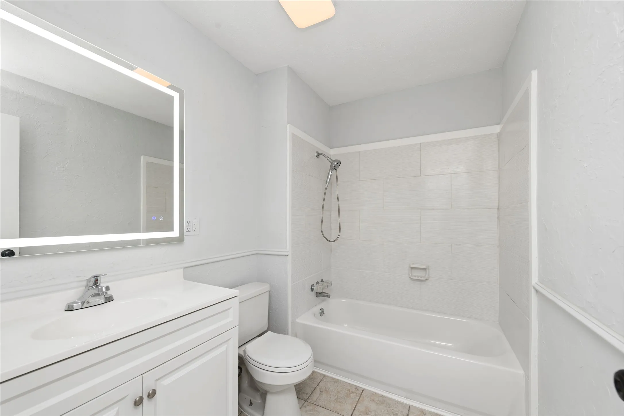 Full bath featuring vanity, bathing tub / shower combination, and light tile patterned flooring