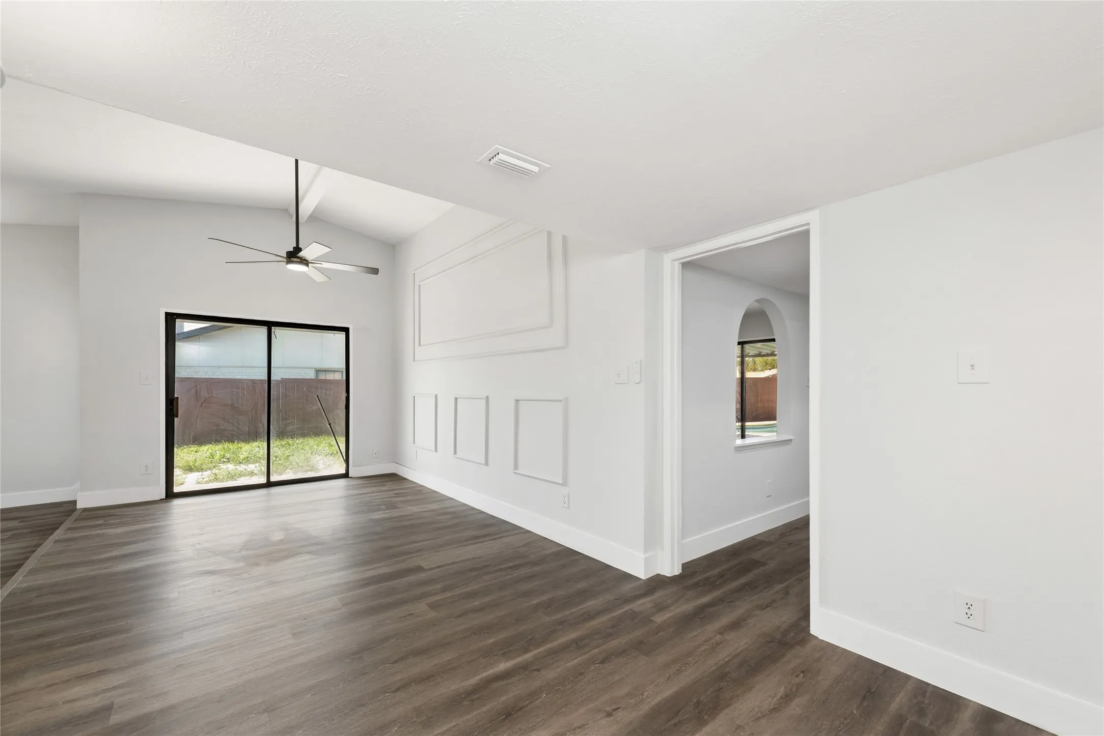 Empty room featuring dark wood-style floors, a ceiling fan, and lofted ceiling