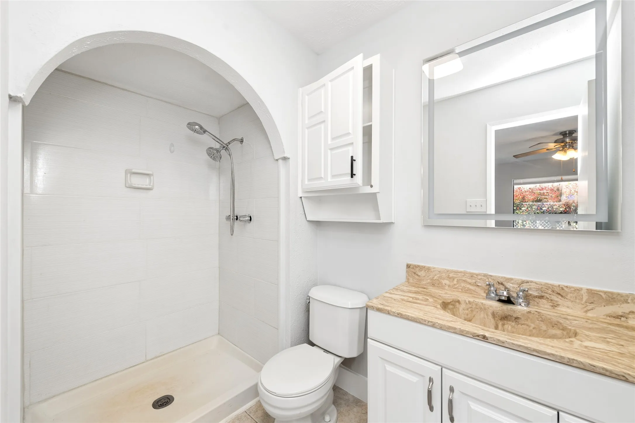 Bathroom with vanity, a shower stall, and ceiling fan