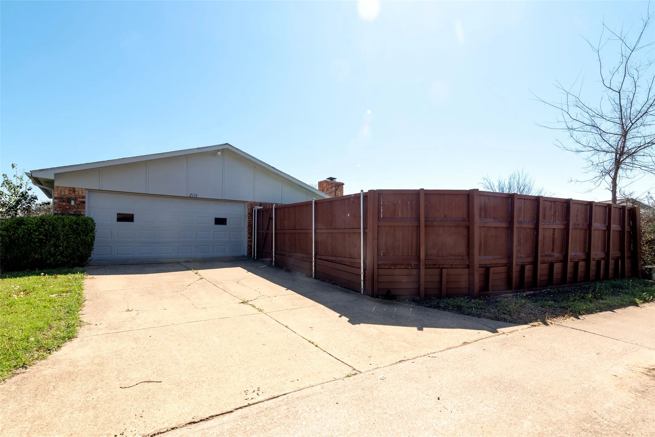 View of back of property featuring a garage, brick siding, concrete driveway, and board and batten siding