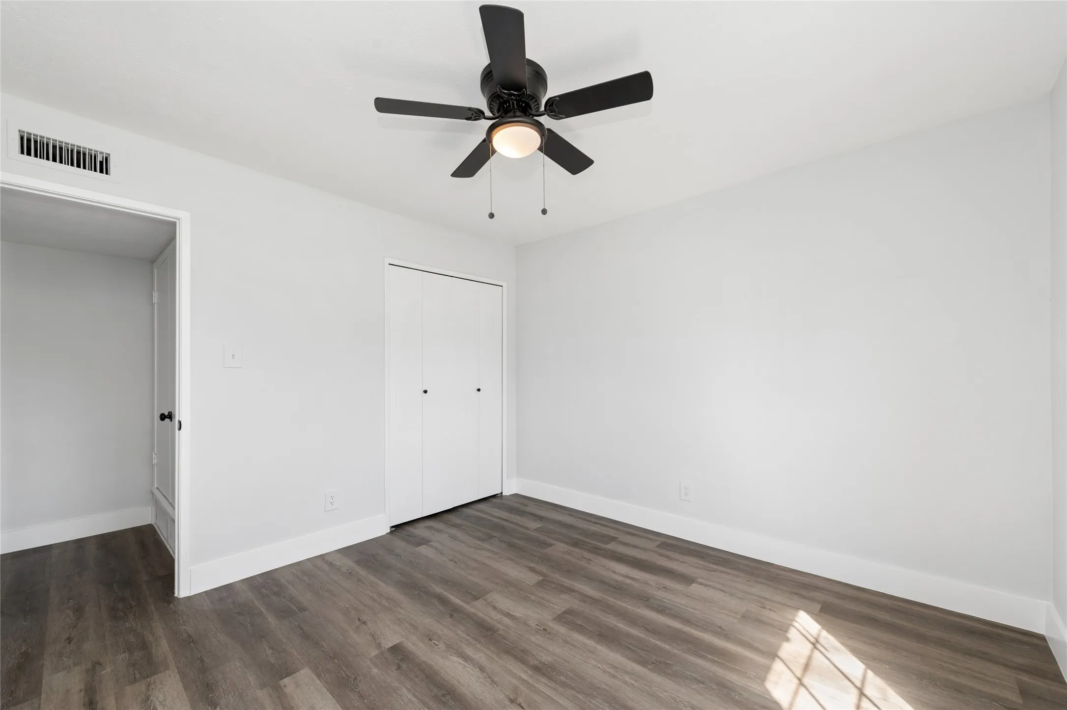 Unfurnished bedroom featuring dark wood finished floors, ceiling fan, and a closet