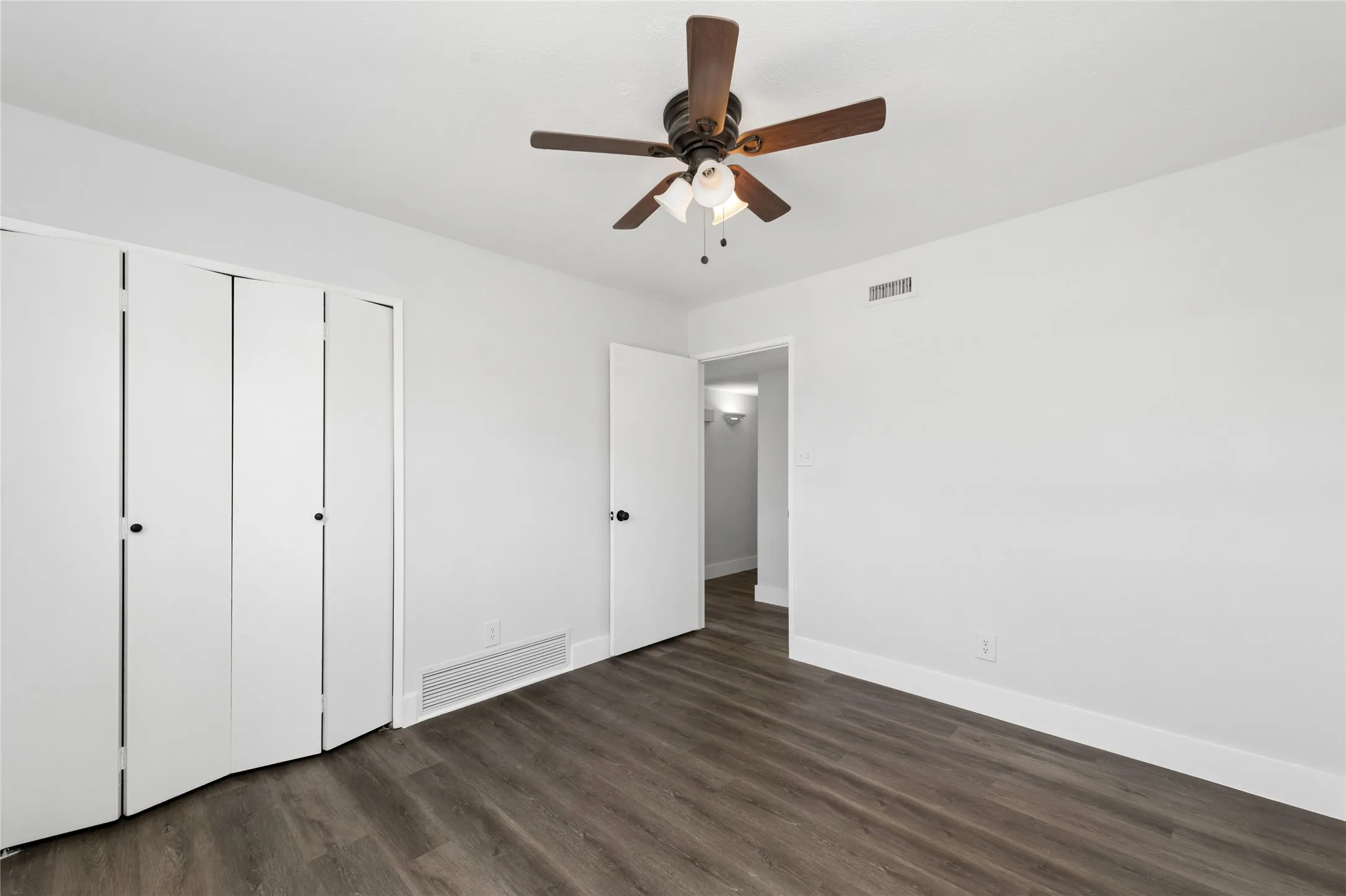 Unfurnished bedroom with a ceiling fan, dark wood-style flooring, and a closet