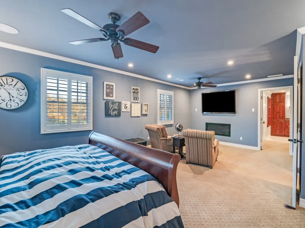 Plantation shutters, separate sitting area with fireplace, and recessed lighting.