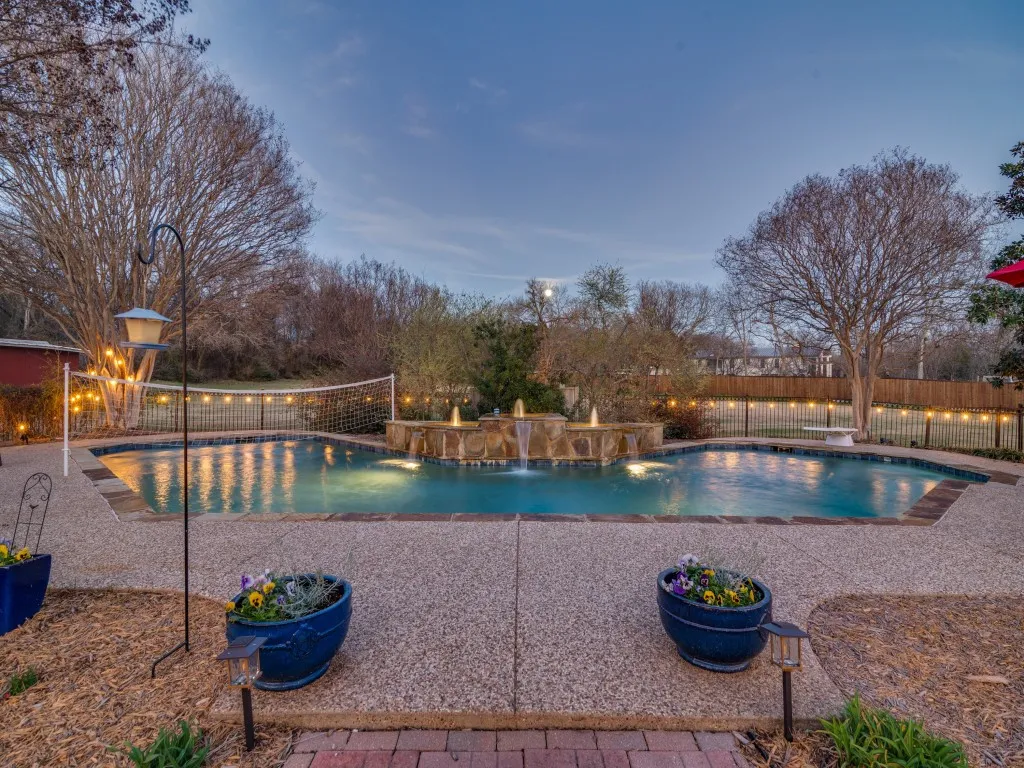 Sunset look at the large inground saltwater pool with water feature.  Pool also features volleyball and diving areas.