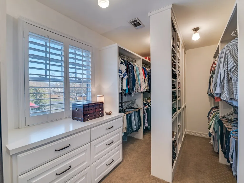 The primary closet boasts built-in shelves, drawers, plantation shutters and a built-in ironing board.  This view is only a partial view of the closet space.