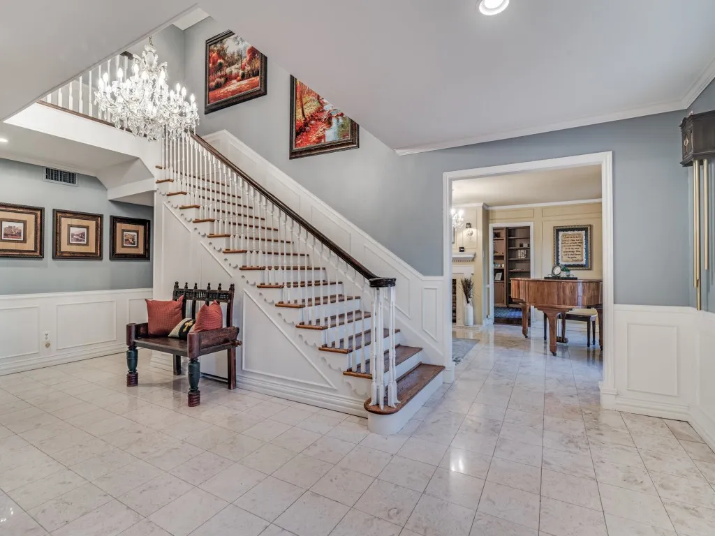 The welcoming entry features marble flooring, chandelier and an extra wide wood staircase.