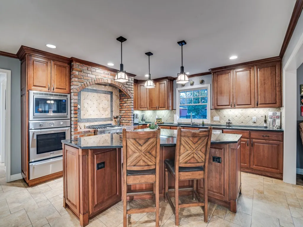 The updated kitchen features a sizable island, stainless Thermador appliances including a gas range, and pendant lighting.