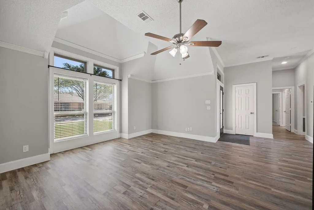 Unfurnished living room featuring ceiling fan, a high textured ceiling, ornamental molding, and dark wood-style floors