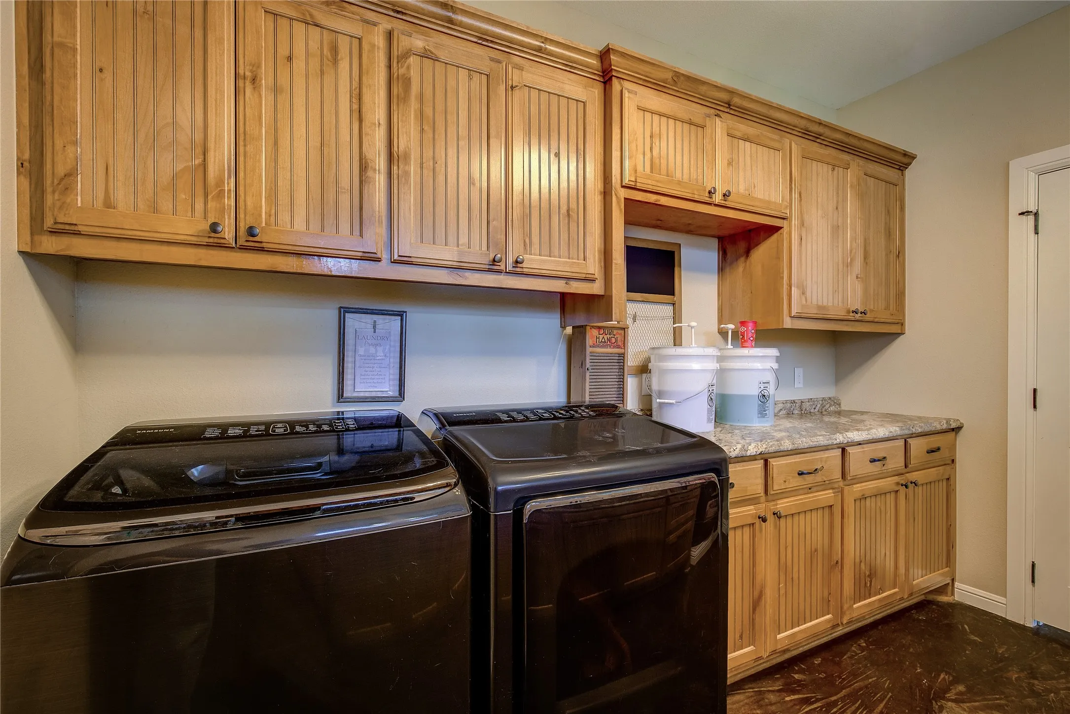 Spacious laundry room measuring 11’7” x 8’9”, featuring a utility sink, abundant cabinet storage, and dedicated areas for hanging and folding clothes.