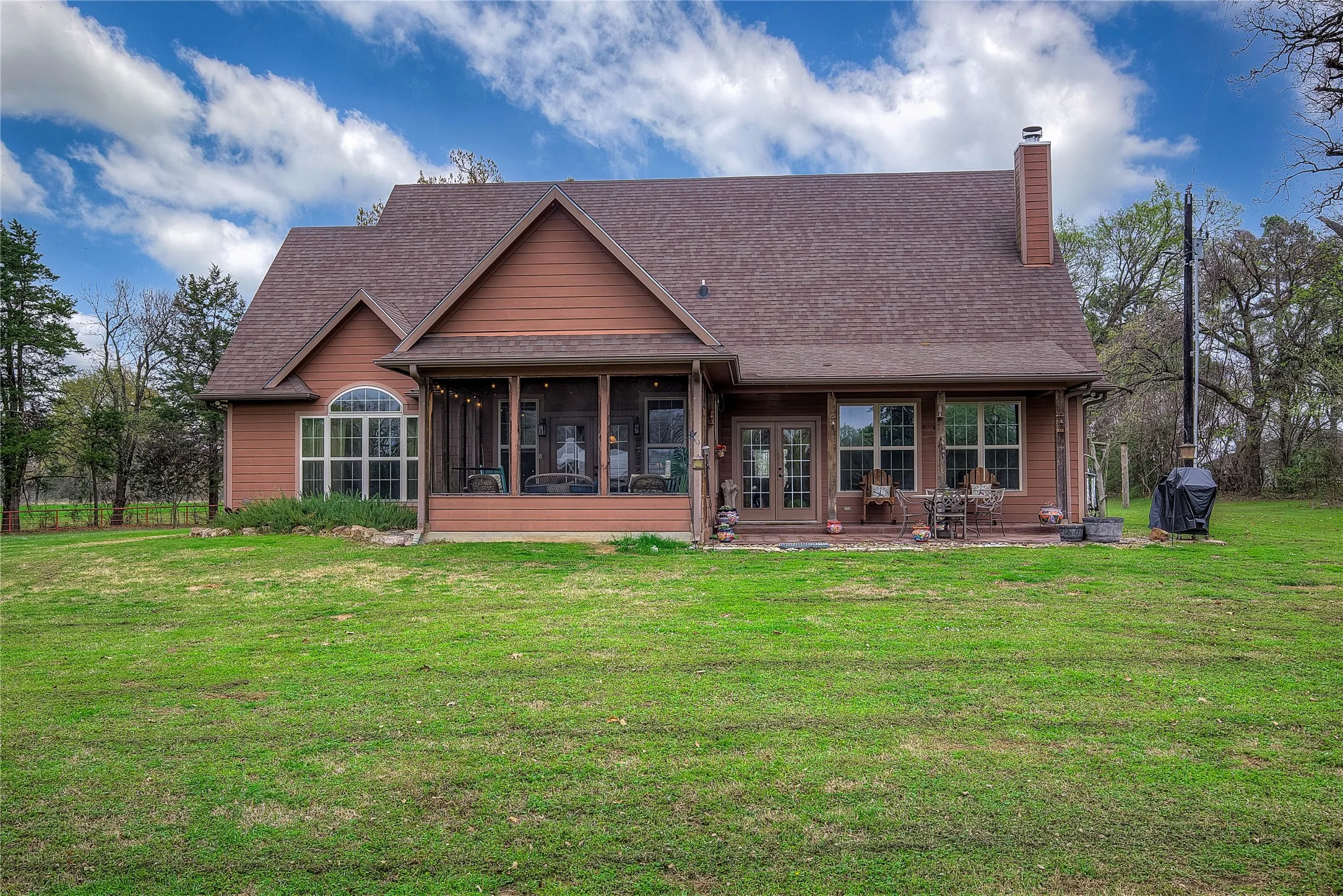 Rear view of the home featuring a screened-in porch and a large back patio with outdoor dining space.