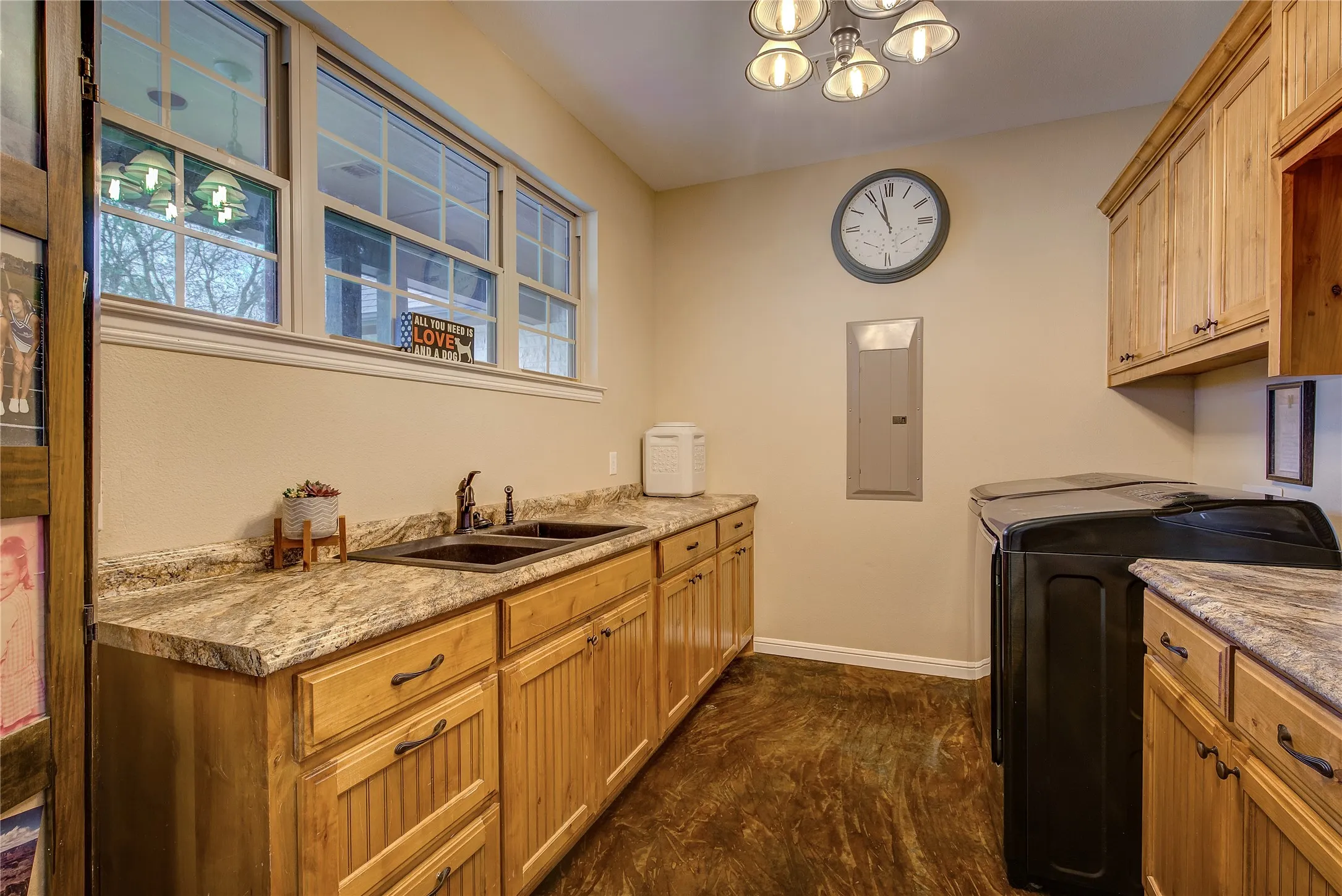 Spacious laundry room measuring 11’7” x 8’9”, featuring a utility sink, abundant cabinet storage, and dedicated areas for hanging and folding clothes.