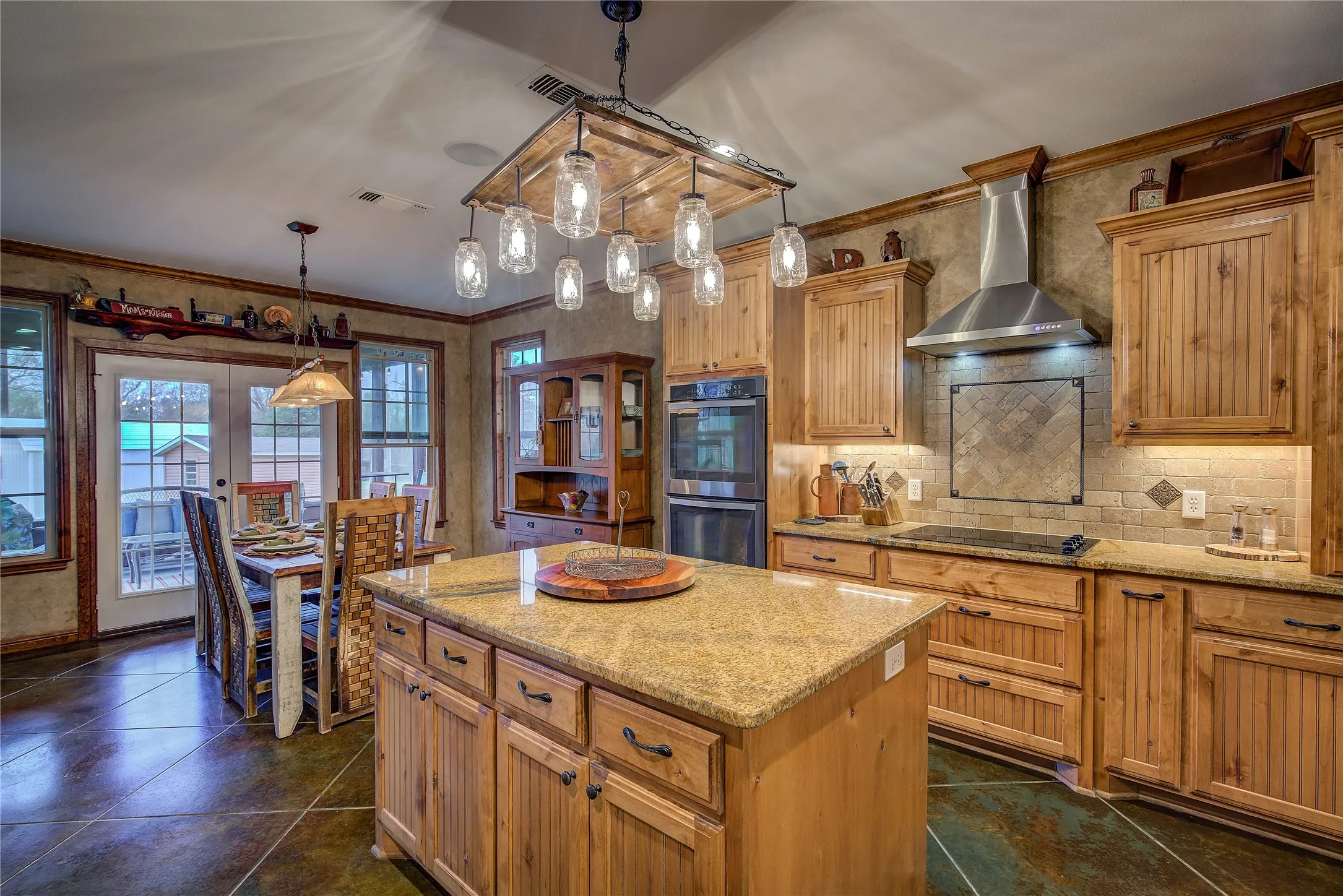 Gourmet eat-in kitchen measuring 23’5” x 14’3”, featuring a large island, double ovens, cooktop, appliance garage, breakfast bar, and custom upgrades throughout.