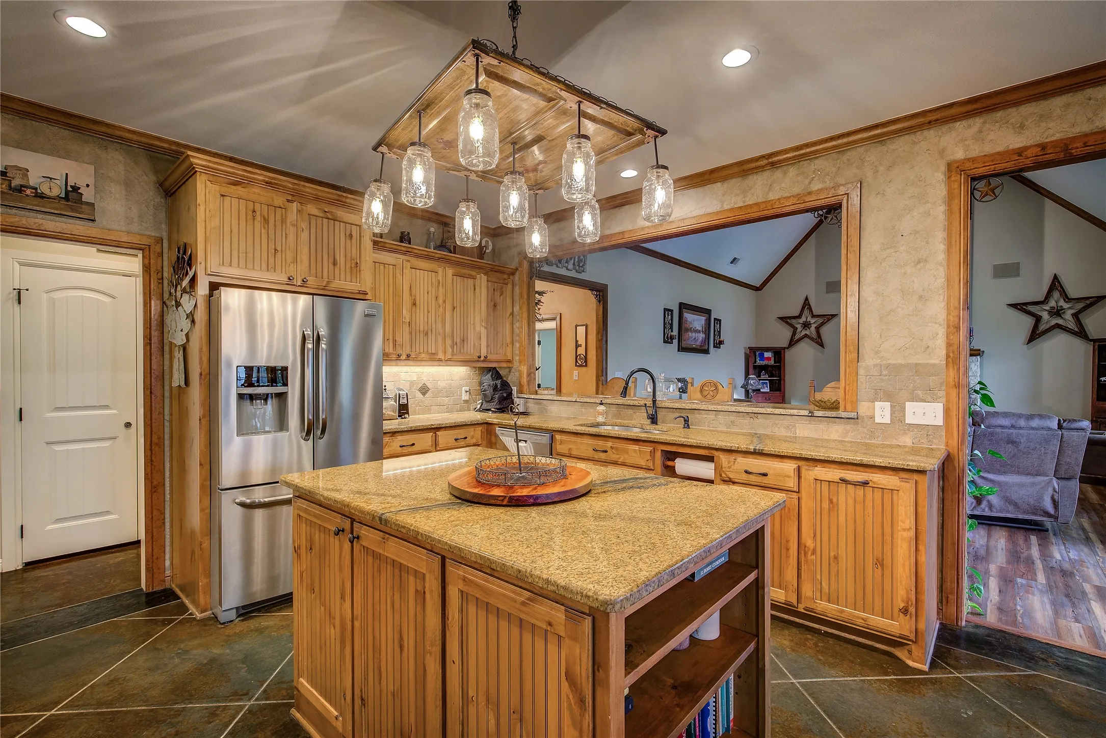 Gourmet eat-in kitchen measuring 23’5” x 14’3”, featuring a large island, double ovens, cooktop, appliance garage, breakfast bar, and custom upgrades throughout.