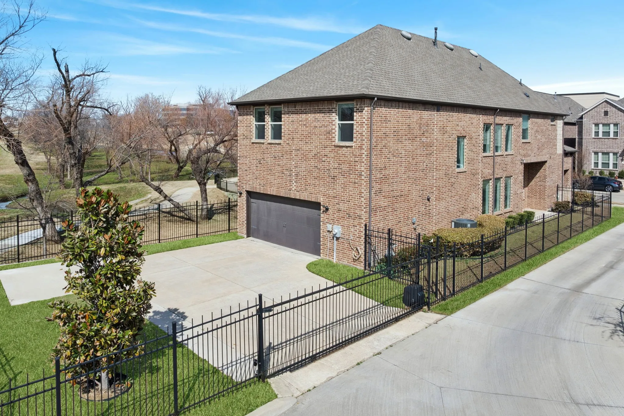 View of property exterior with a fenced front yard, brick siding, an attached garage, and driveway