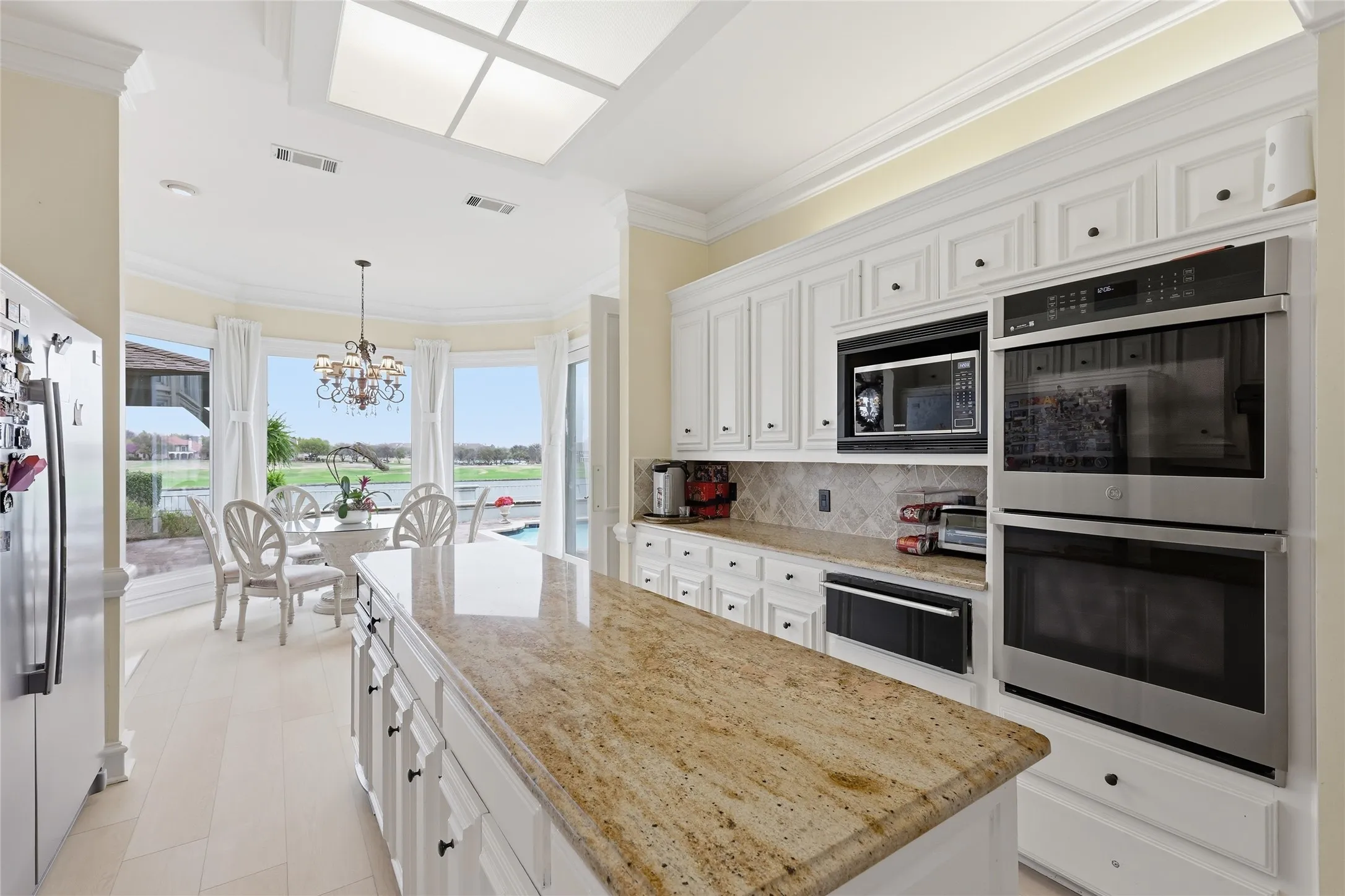 Kitchen featuring stainless steel appliances, white cabinets, crown molding, a kitchen island, and light stone​​‌​​​​‌​​‌‌​‌‌​​​‌‌​‌​‌​‌​​​‌​​ counters
