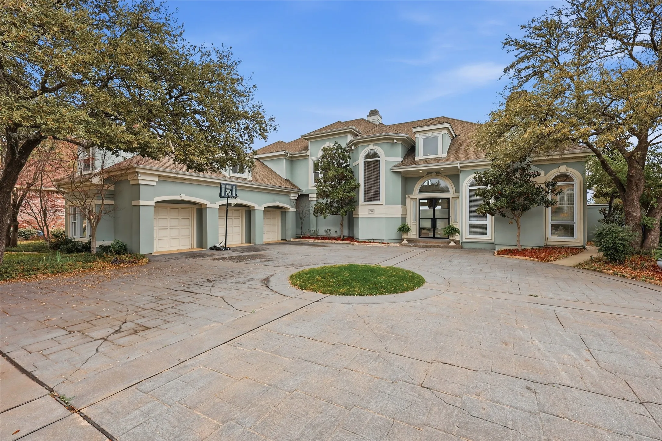 Mediterranean / spanish-style home with curved driveway, stucco siding, french doors, and a chimney