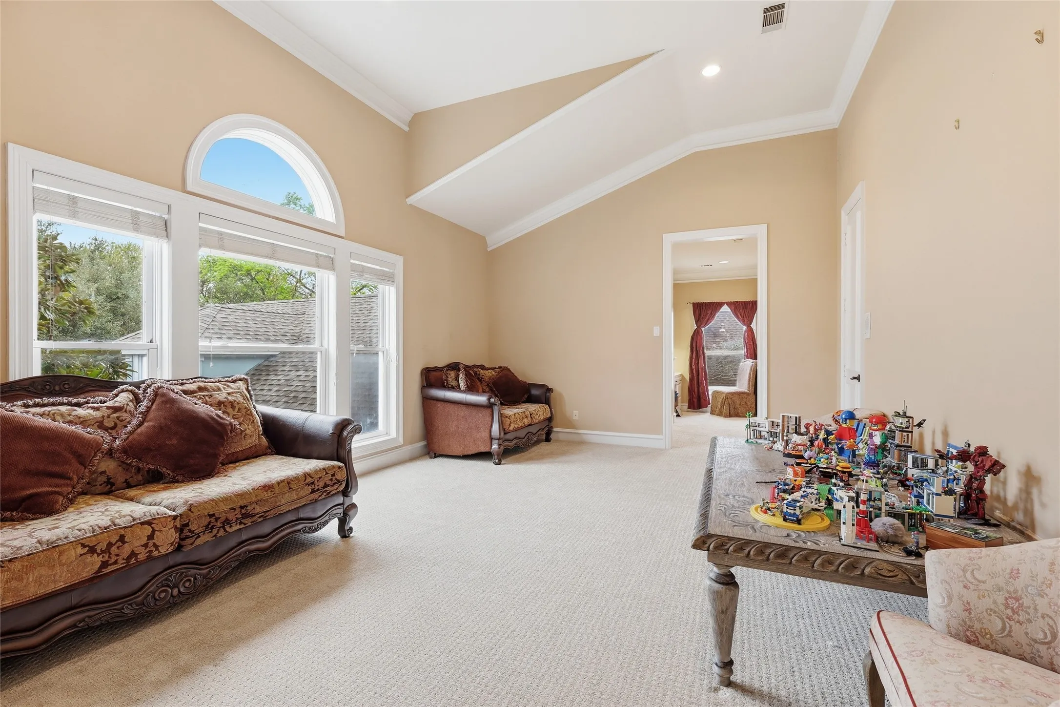 Living area featuring crown molding, lofted ceiling, and light carpet