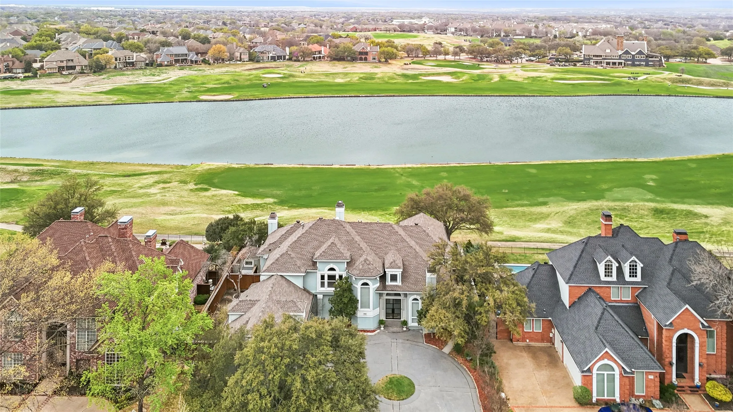 Aerial perspective of suburban area with a nearby body of water and a local golf course